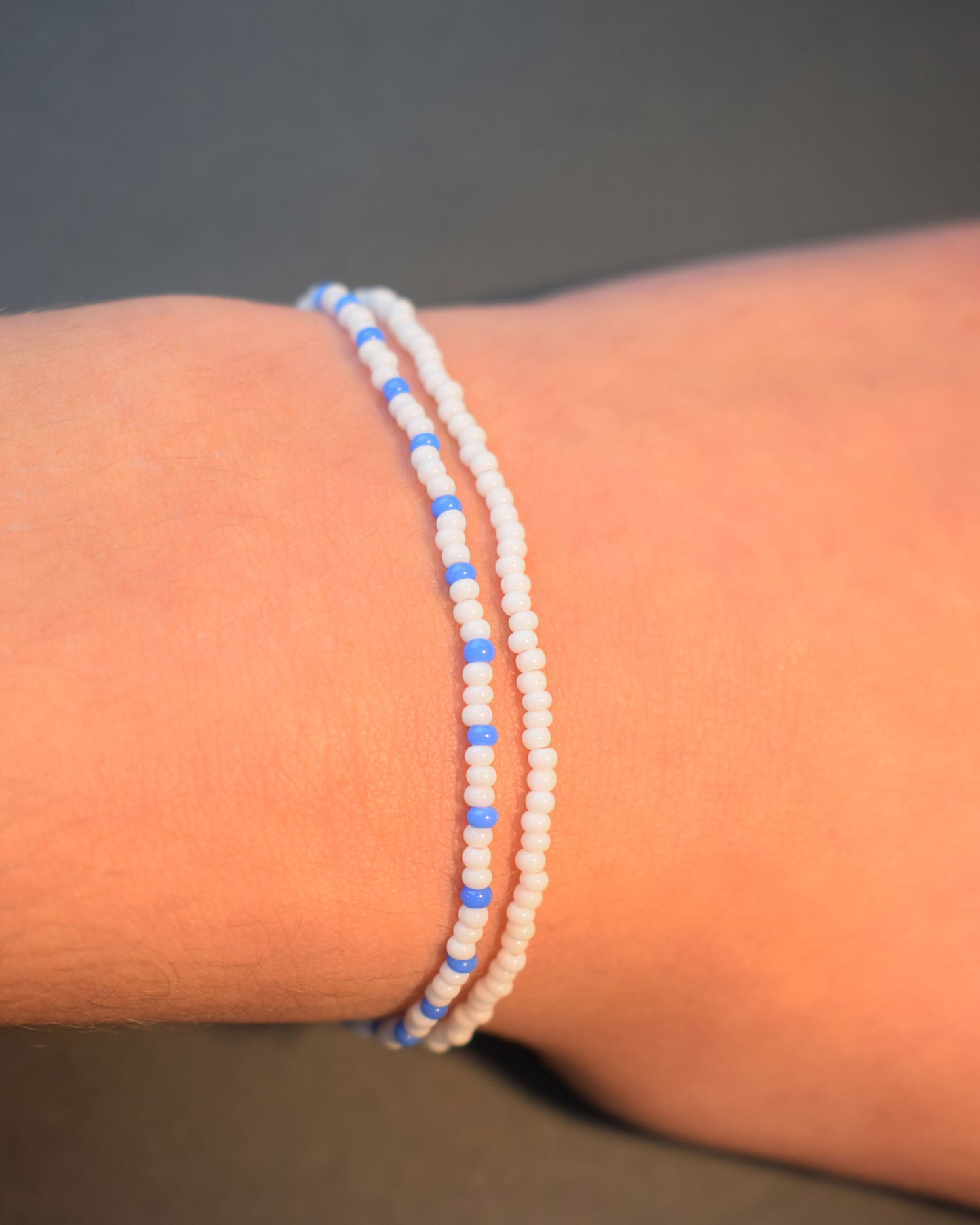 Pulseira dupla de missangas, uma branca e outra com padrão azul neon. Leve e vibrante, ideal para um look moderno e descontraído.