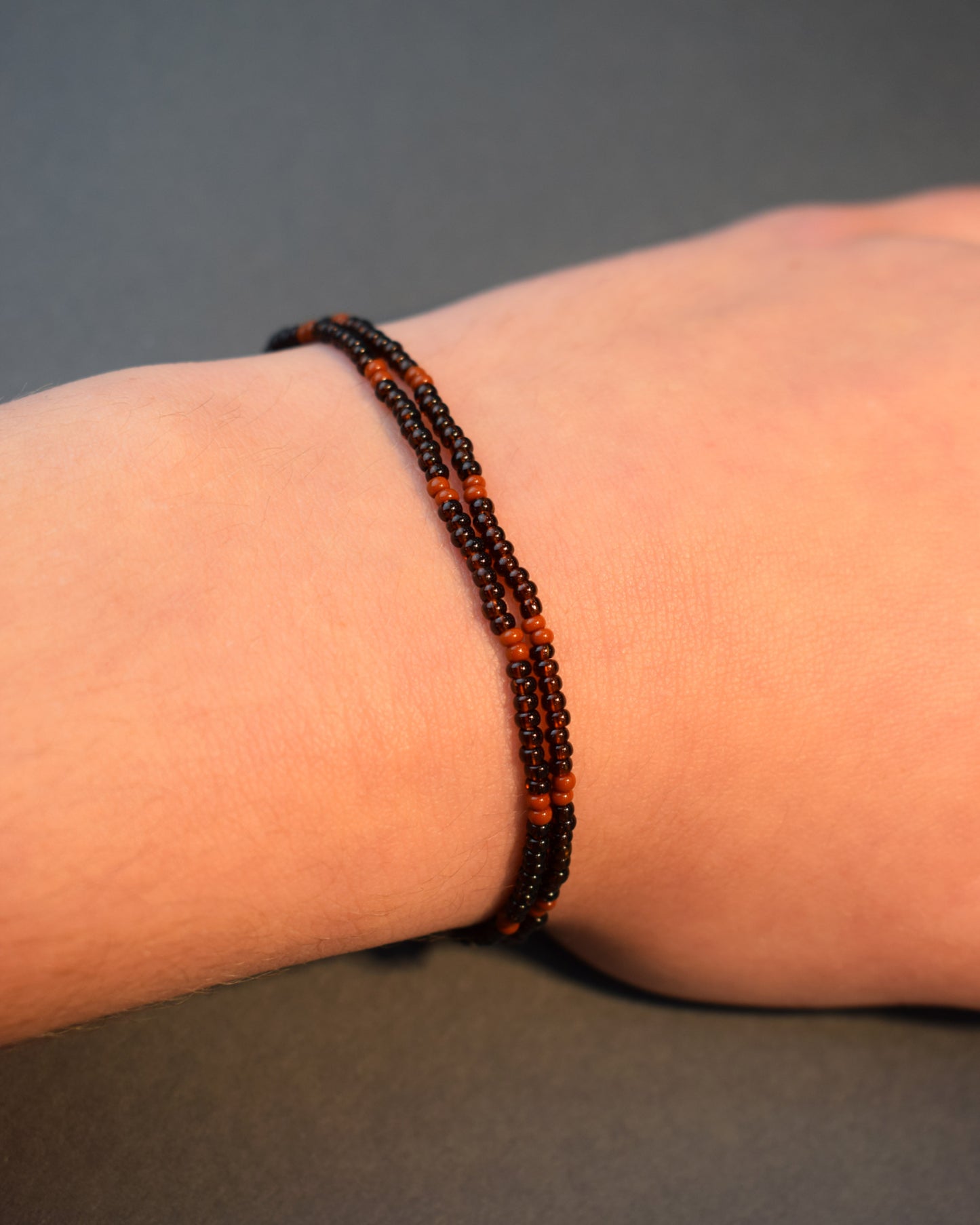 Pulseira dupla de missangas castanhas semitransparentes com padrão castanho opaco. Elegante e versátil, ideal para um look natural e sofisticado.