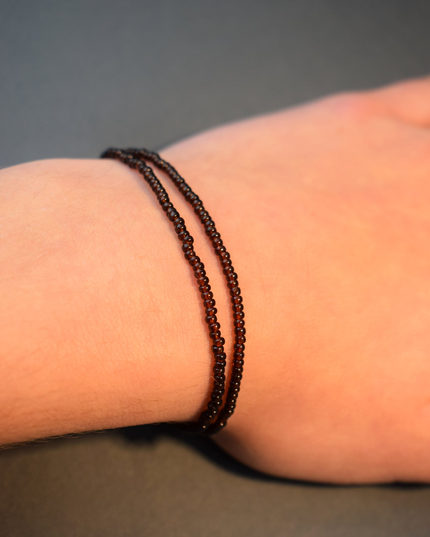 Pulseira dupla com missangas castanhas semitransparentes. Design artesanal e elegante para um toque sofisticado no seu look.