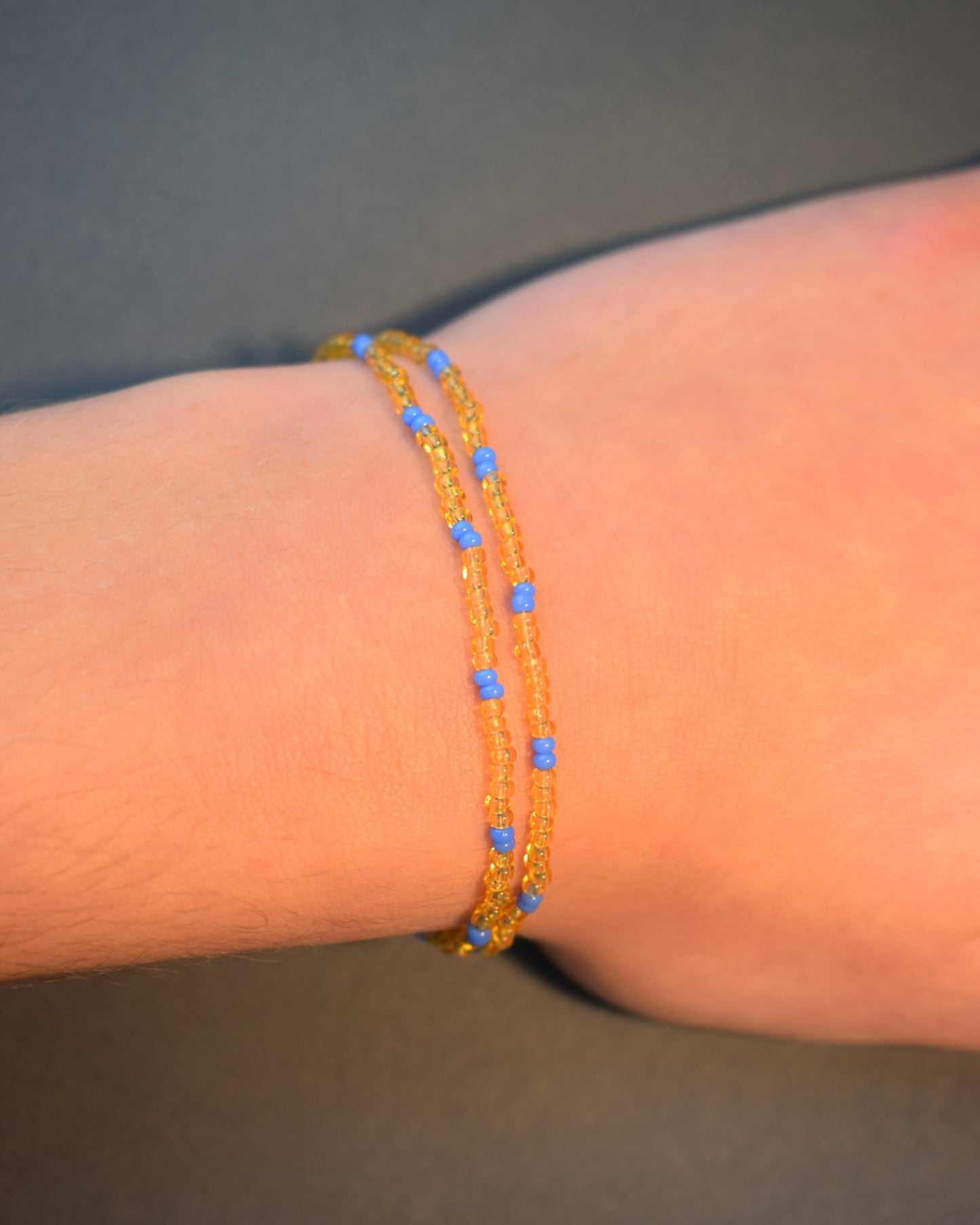 Pulseira dupla com missangas douradas semitransparentes e padrão azul neon. Design moderno e elegante para um look vibrante.