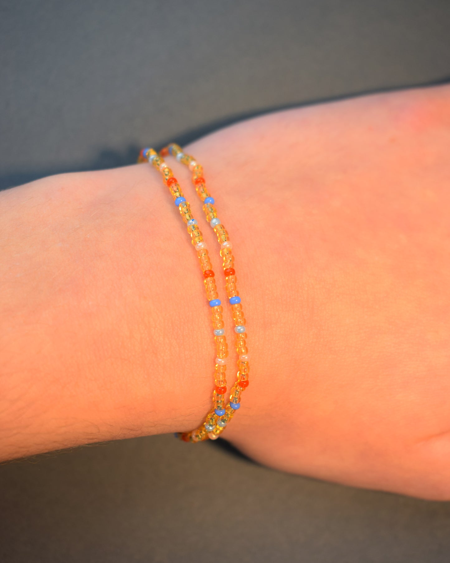 Pulseira dupla com missangas douradas semitransparentes e padrão multicolor. Design artesanal vibrante, perfeito para um look sofisticado e moderno.