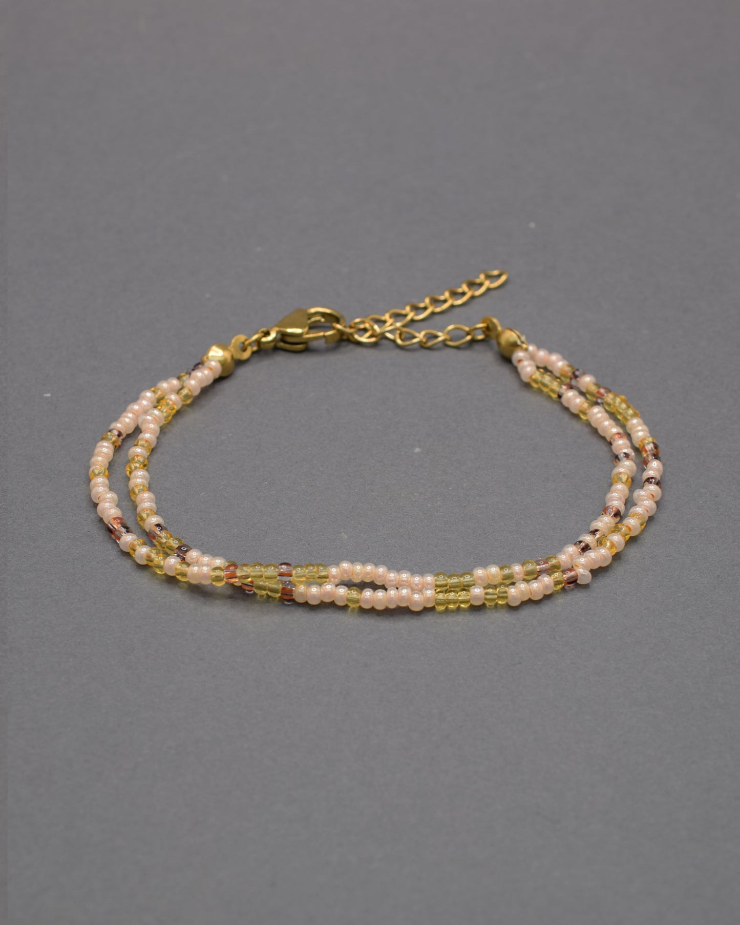 Pulseira dupla artesanal em mix dourado, combinando missangas luminosas para um look elegante e versátil, ideal para realçar qualquer estilo.