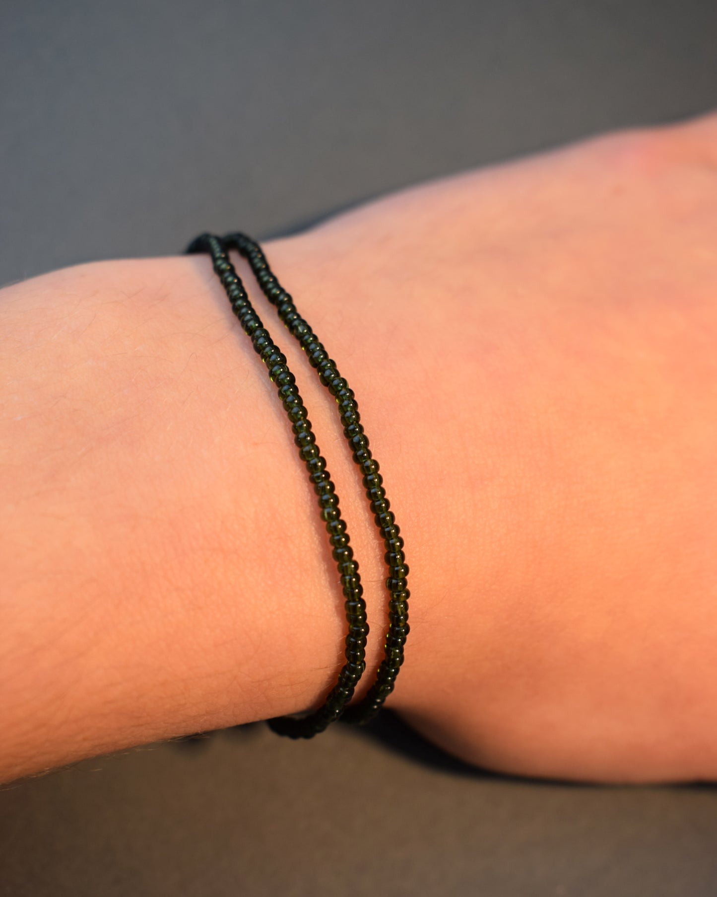 Pulseira dupla de missangas verde escuras semitransparentes. Design artesanal e elegante, ideal para um look sofisticado.