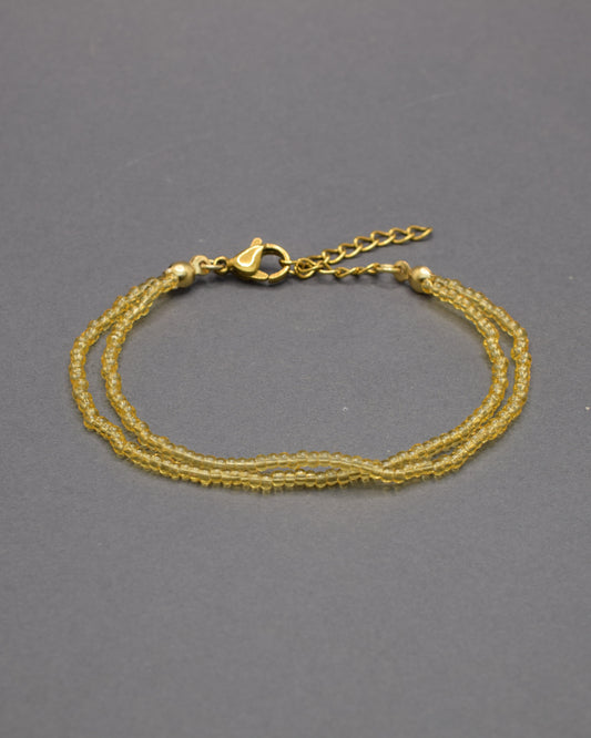 Pulseira dupla com missangas douradas semitransparentes. Elegância artesanal com brilho subtil, perfeita para um look sofisticado e intemporal.