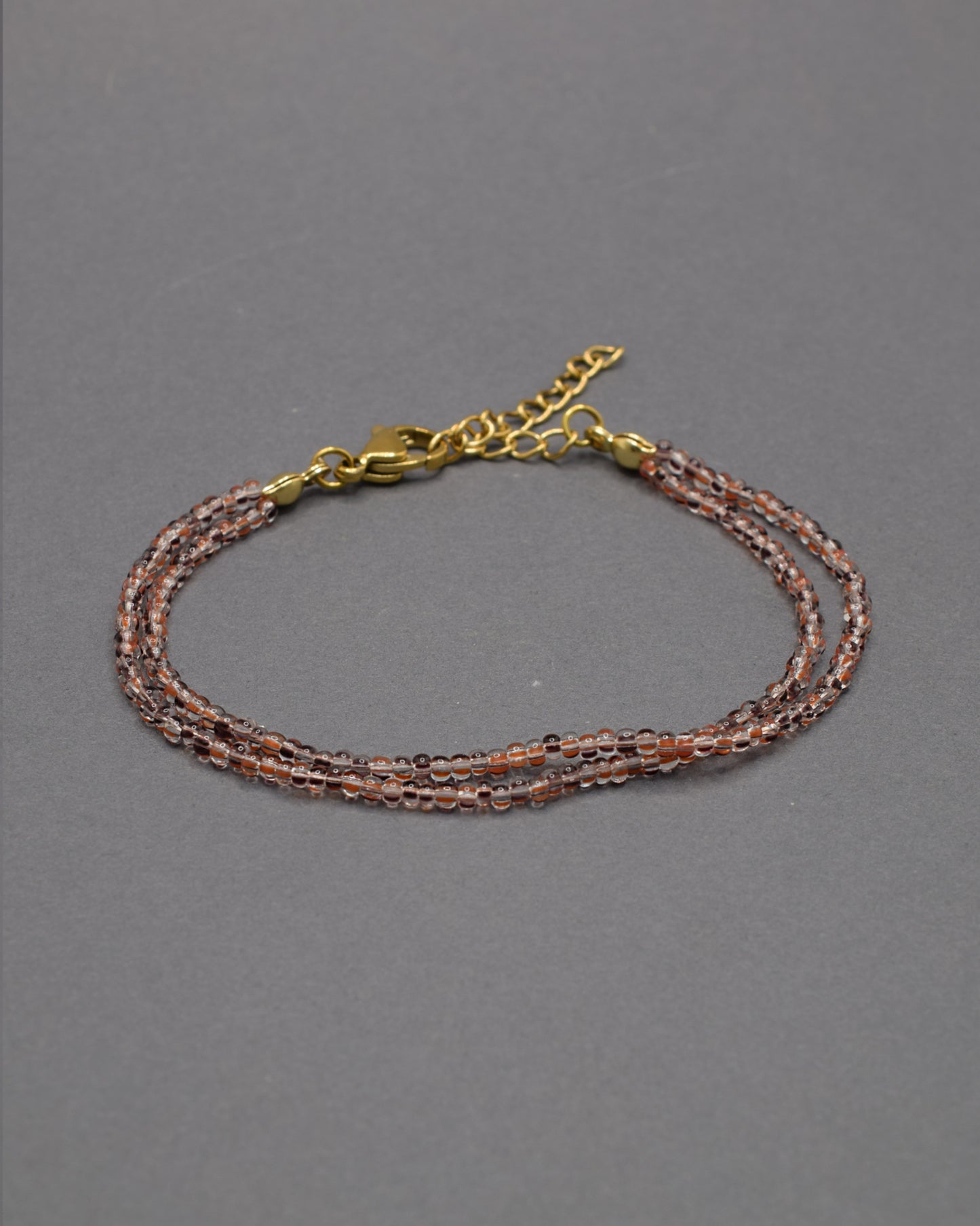 Pulseira Dupla de Missangas Listradas Castanhas, com design elegante e moderno. Perfeita para adicionar sofisticação ao seu estilo.