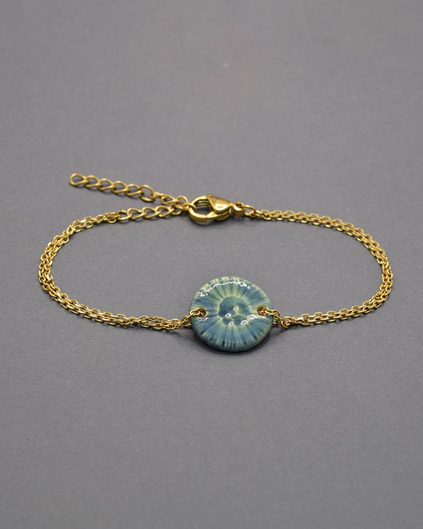 Pulseira delicada com pendente flor do mar em cerâmica verde musgo, inspirada na natureza e perfeita para um toque orgânico e sofisticado ao seu look.