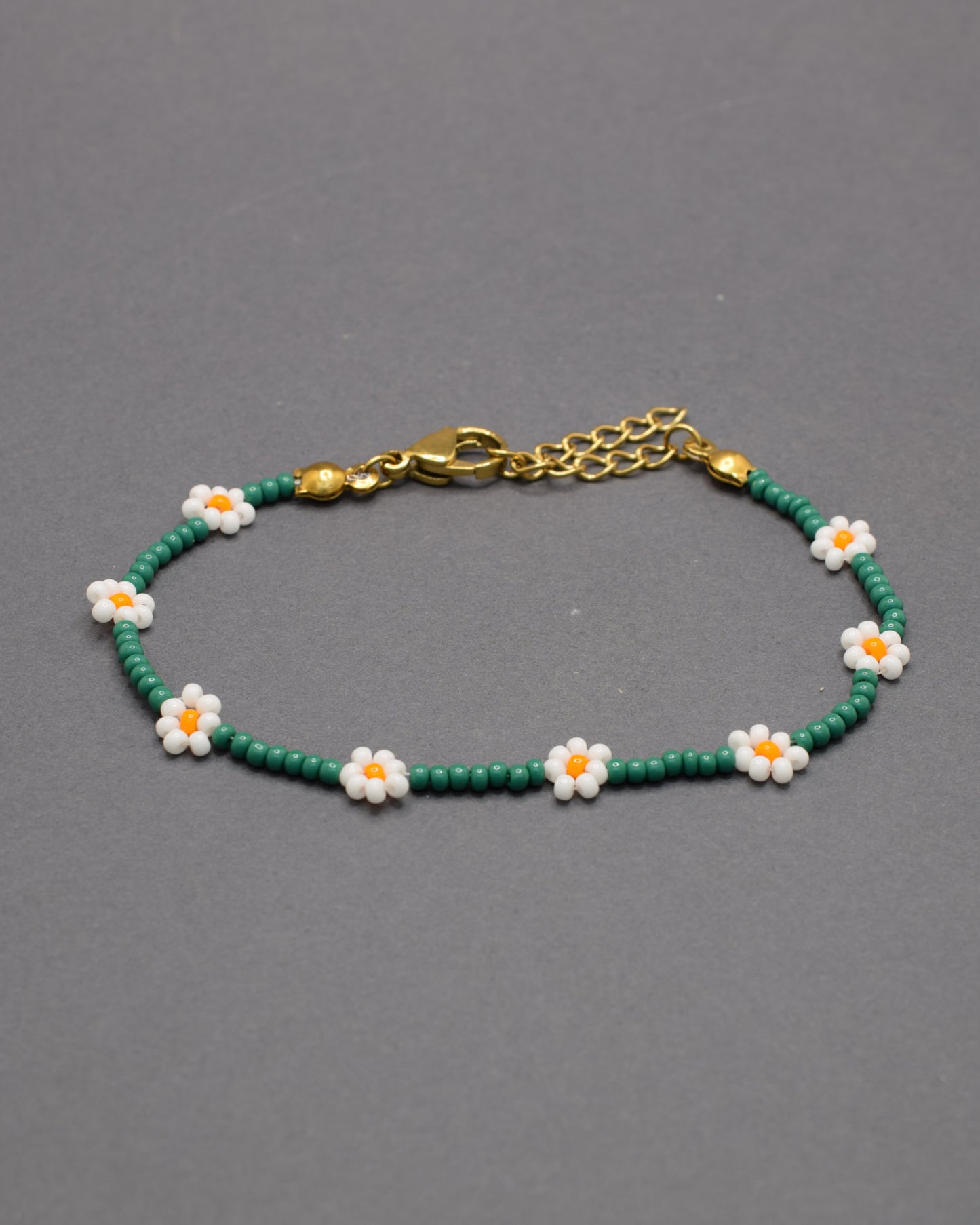 Pulseira de flores brancas com missangas verdes, elegante e natural, ideal para um look fresco e sofisticado com inspiração na natureza.
