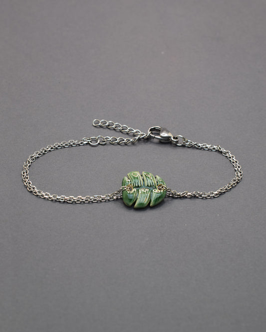 Pulseira delicada com pendente de folha verde em cerâmica, inspirada na natureza, leve e elegante para um toque fresco e sofisticado no seu dia a dia.