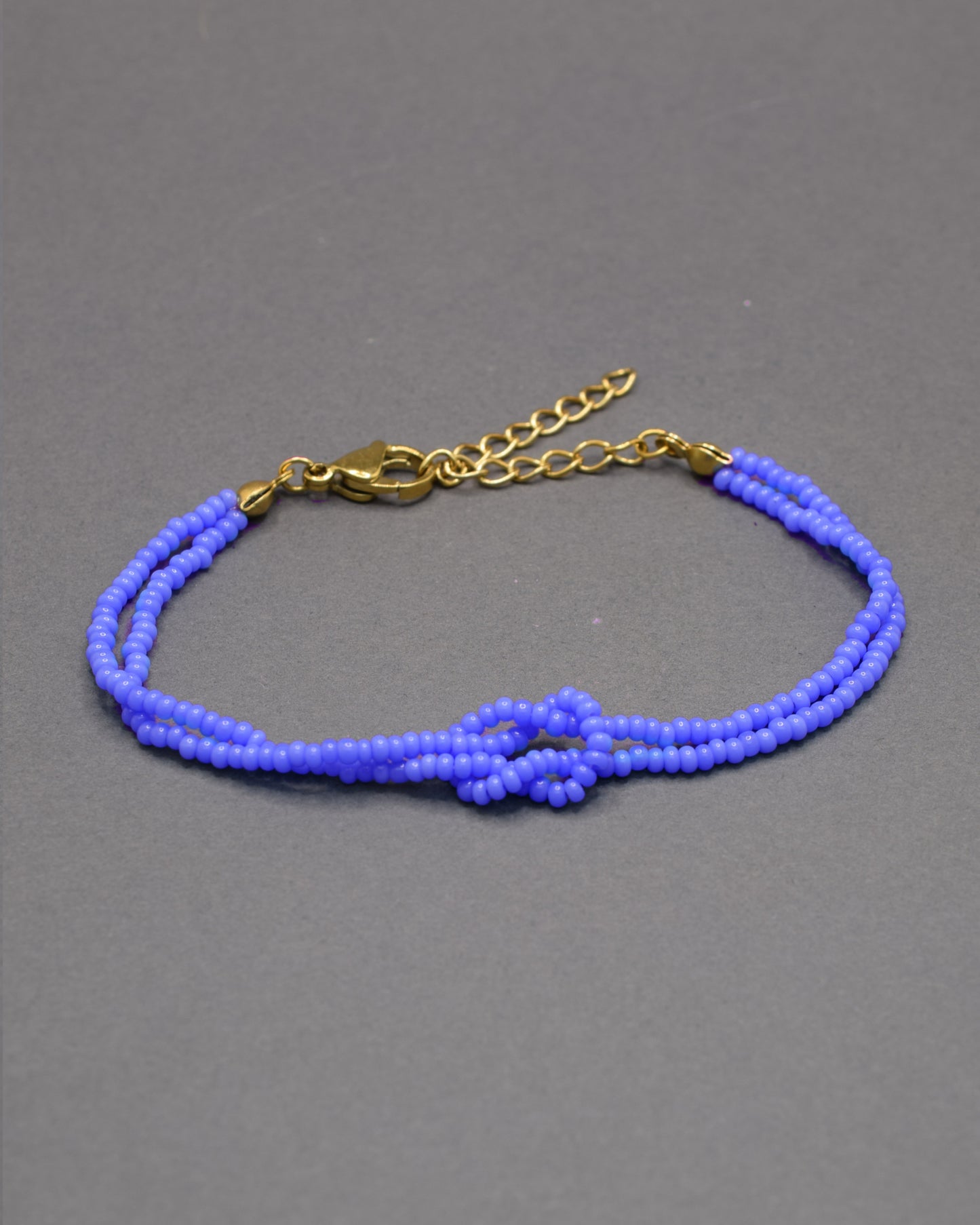 Pulseira dupla de missangas azul neon com nó, vibrante e leve, perfeita para dar um toque luminoso e moderno ao teu look.