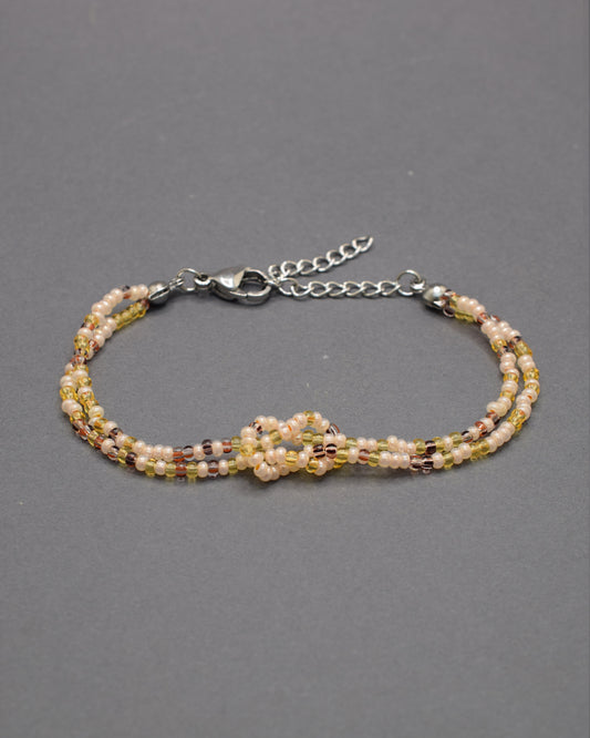 Pulseira dupla de missangas mix dourado com nó, elegante e luminosa, perfeita para acrescentar um toque subtil de brilho ao teu look diário.