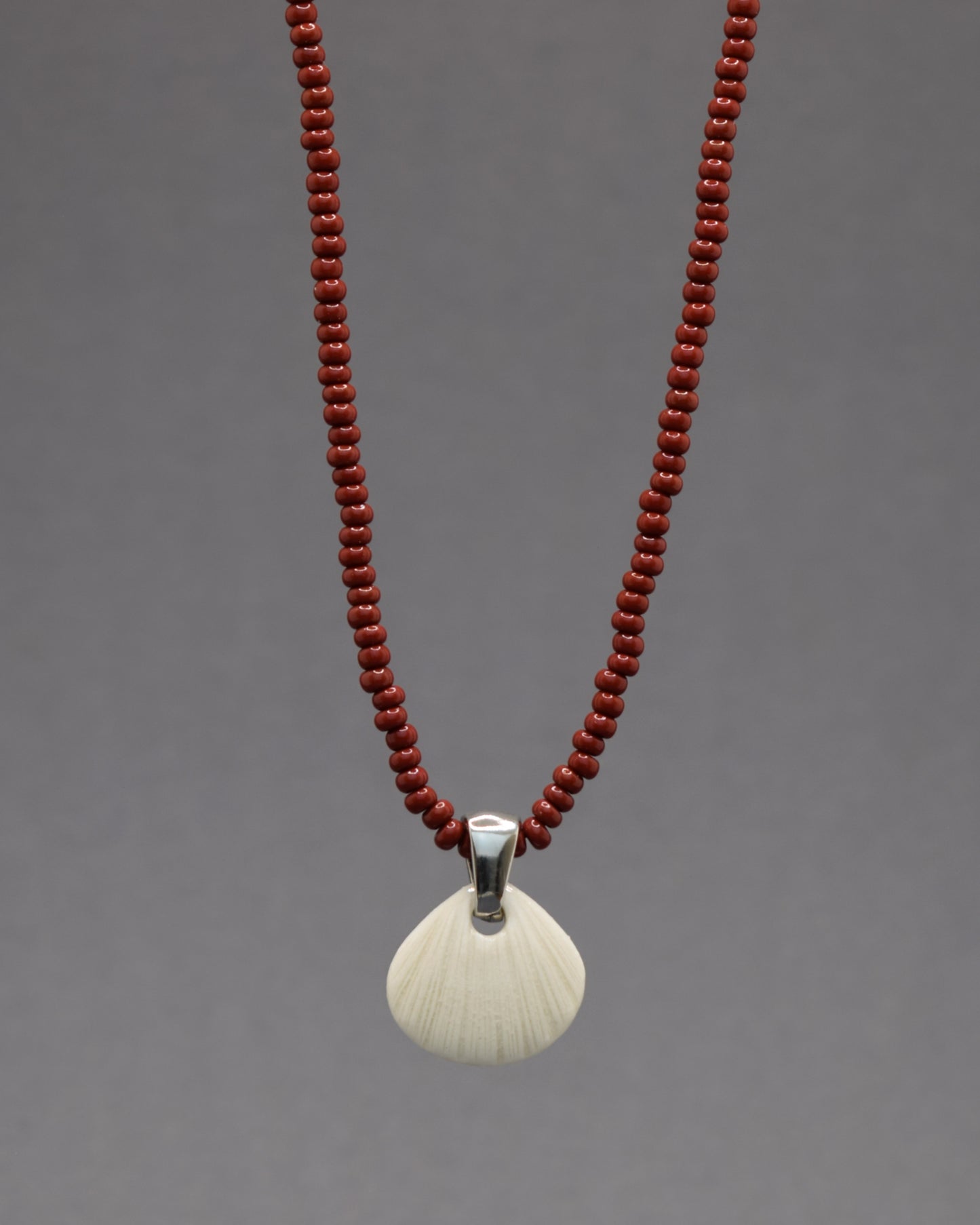 Colar com pendente de porcelana em forma de concha. Peça delicada, feita à mão, ideal para amantes do mar e do design artesanal.