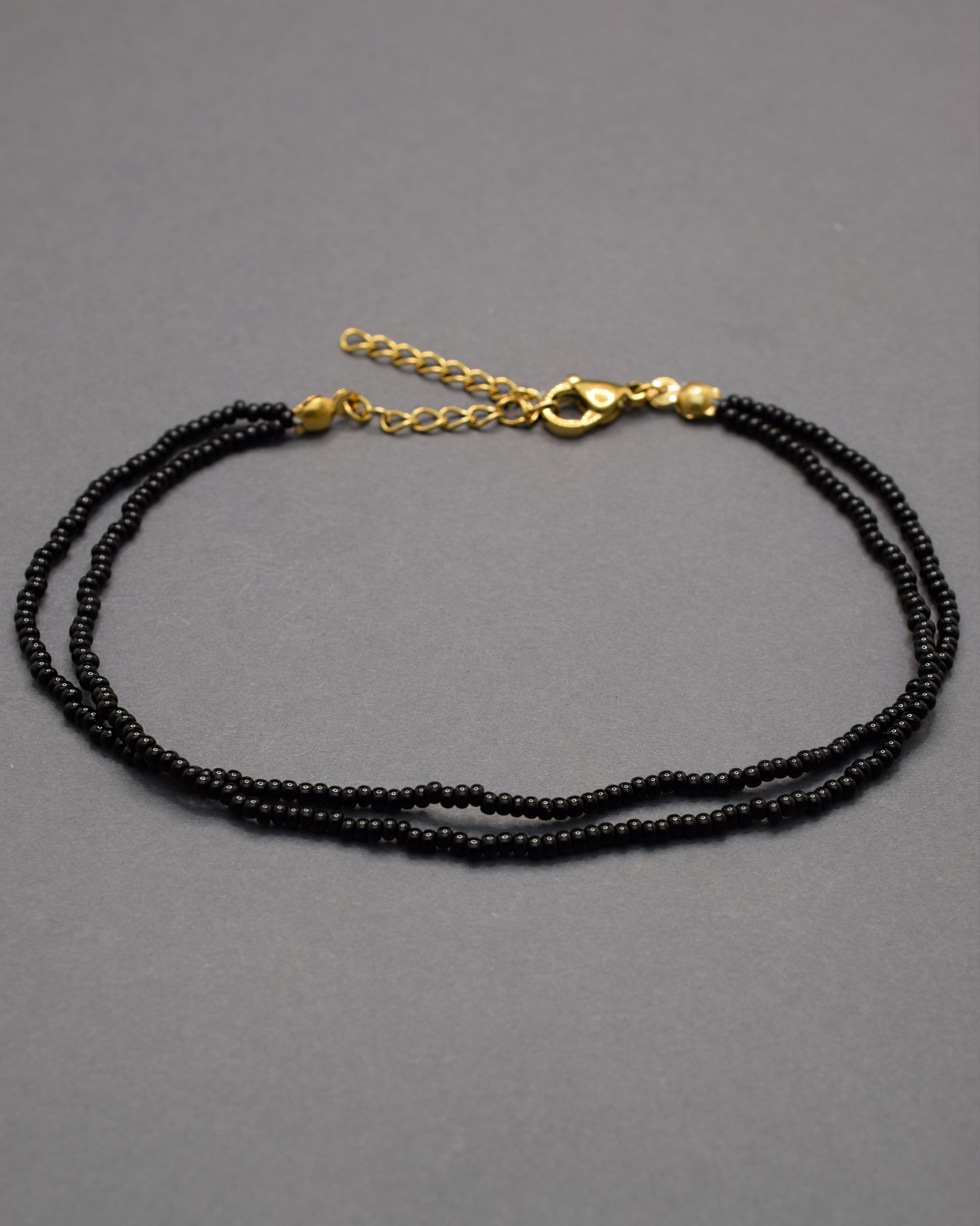 Pulseira dupla de tornozelo com missangas pretas, elegante e intemporal, perfeita para um toque discreto e sofisticado no teu estilo.