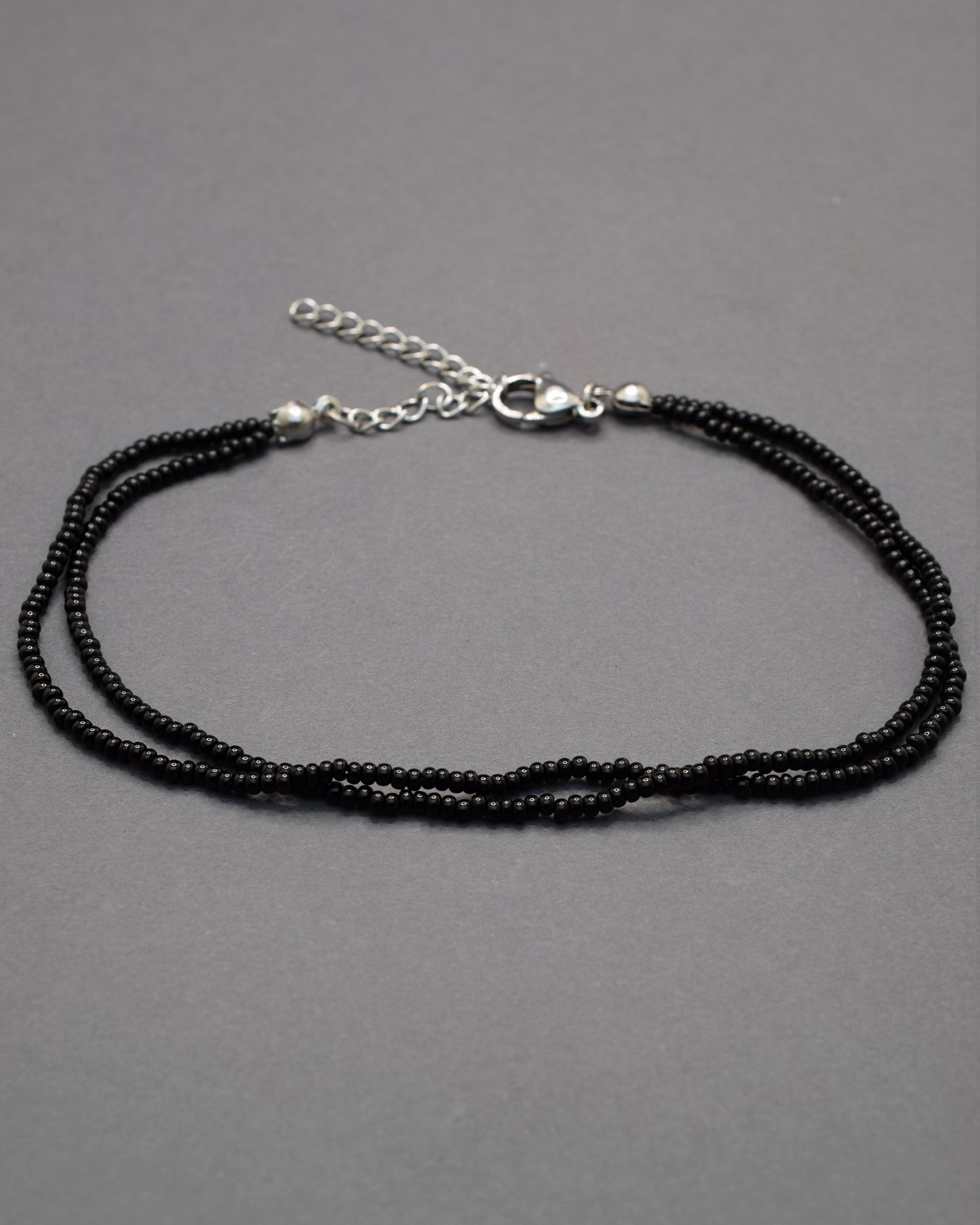 Pulseira dupla de tornozelo com missangas pretas, elegante e intemporal, perfeita para um toque discreto e sofisticado no teu estilo.