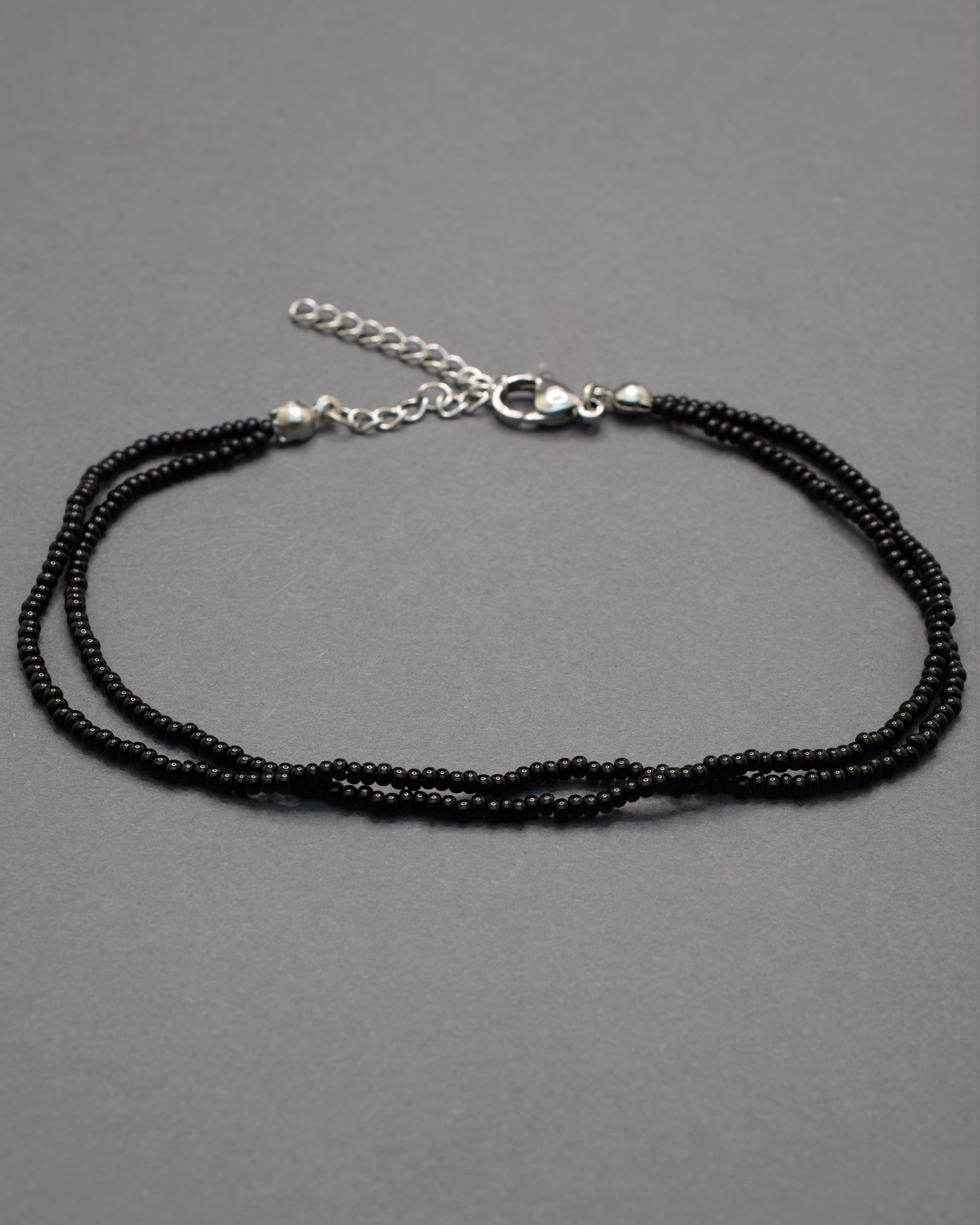Pulseira dupla de tornozelo com missangas pretas, elegante e intemporal, perfeita para um toque discreto e sofisticado no teu estilo.