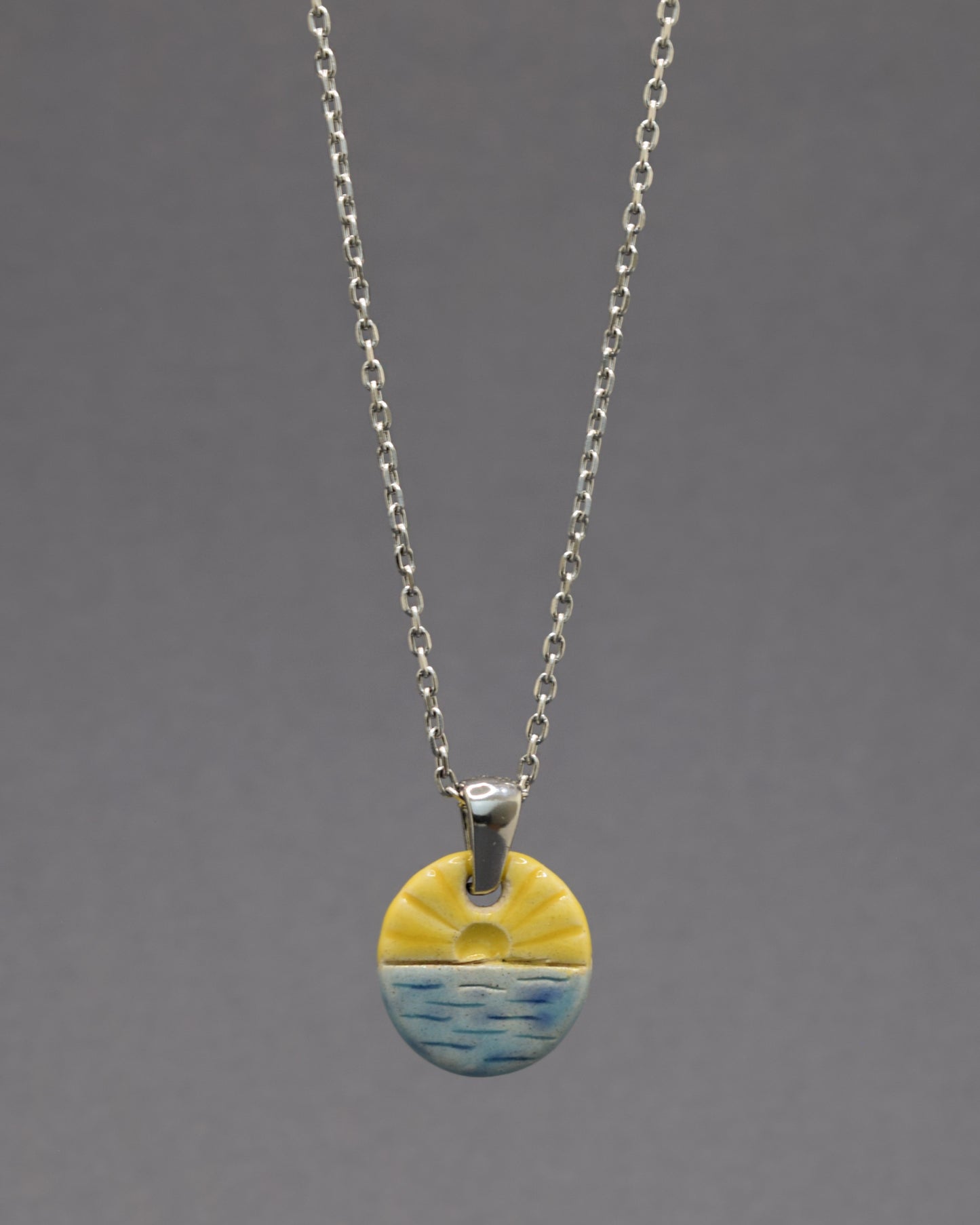 Colar com pendente de sol nascente, símbolo de novos começos e energia positiva para iluminar seu dia.