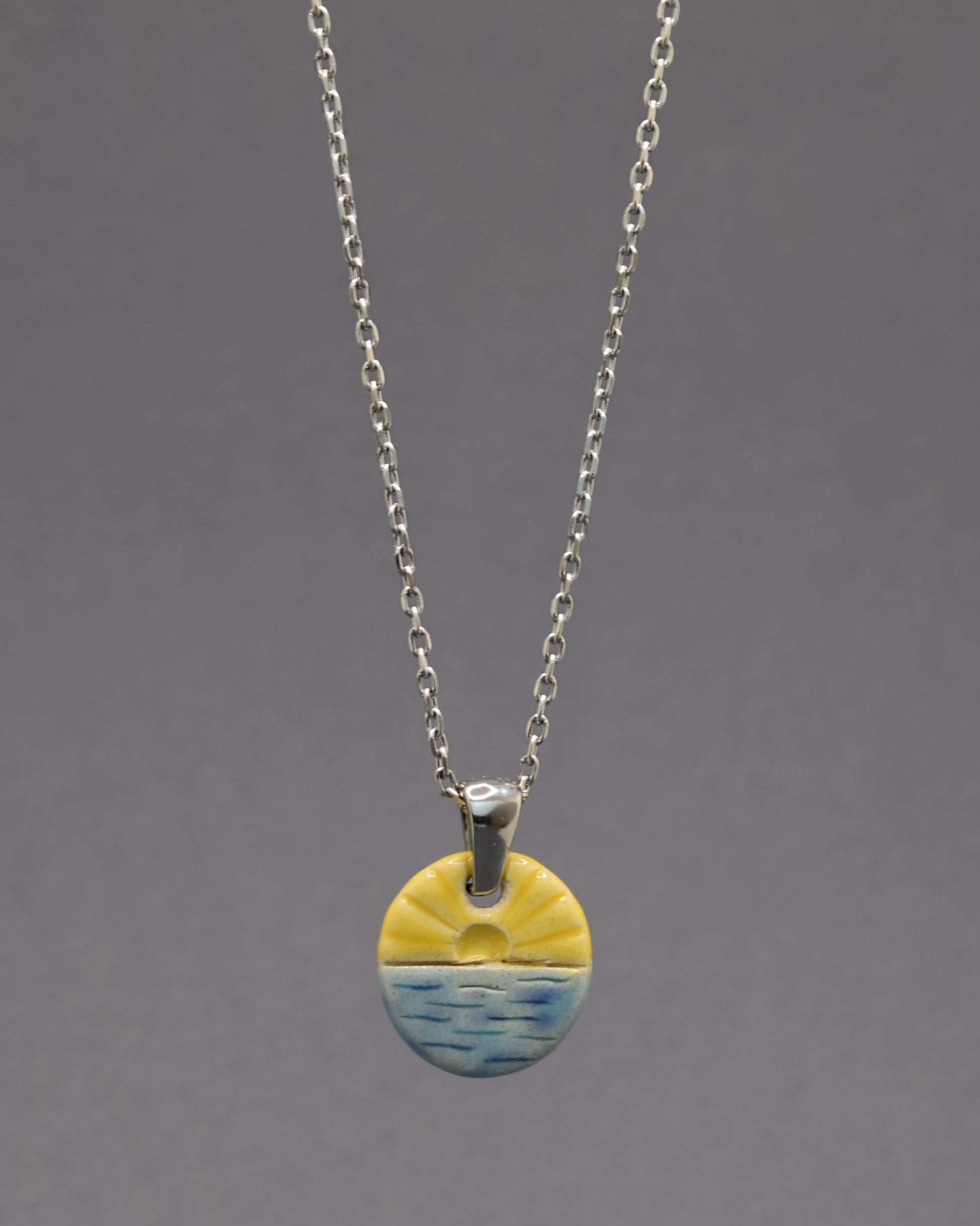 Colar com pendente de sol nascente, símbolo de novos começos e energia positiva para iluminar seu dia.