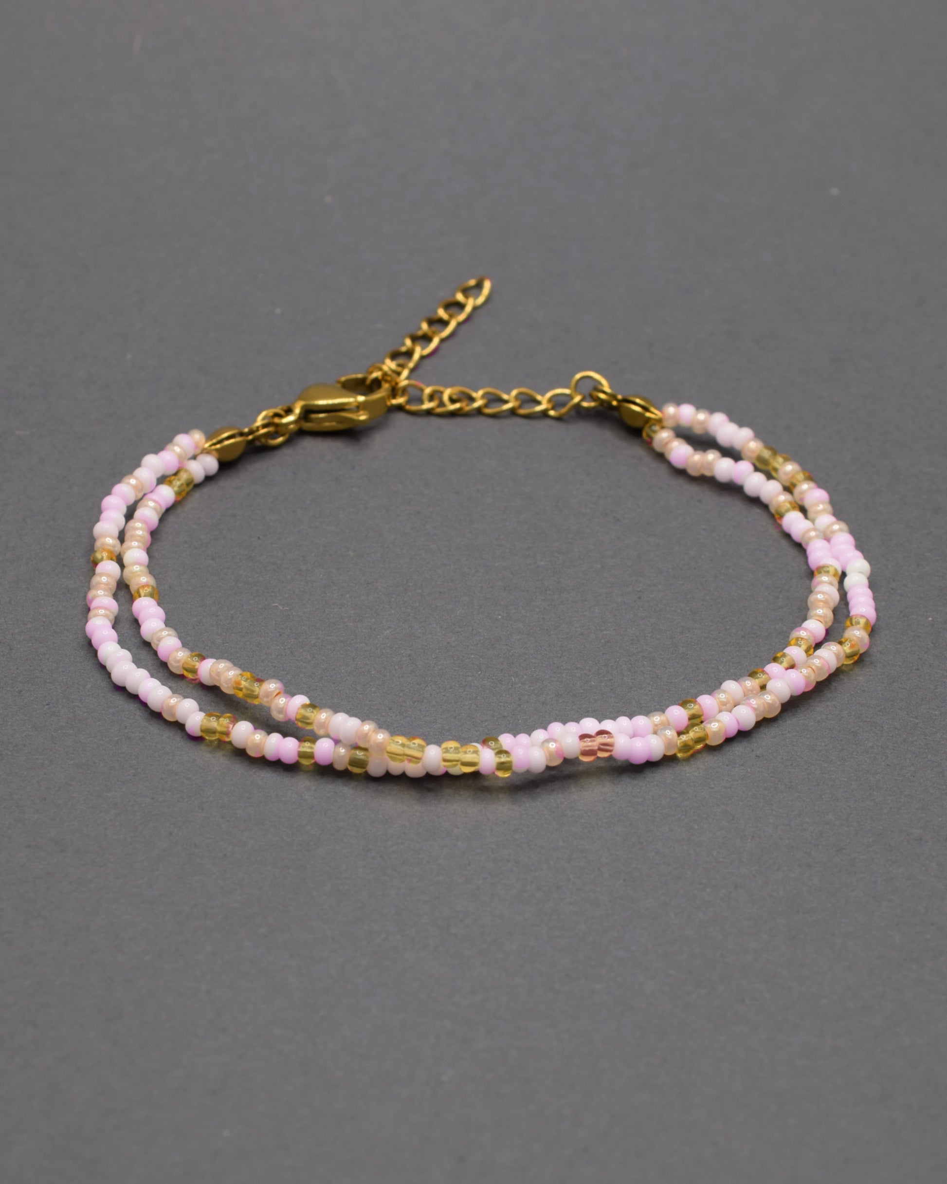Pulseira dupla de missangas em tons de rosa e dourado, combinando delicadeza e estilo num design vibrante e elegante.