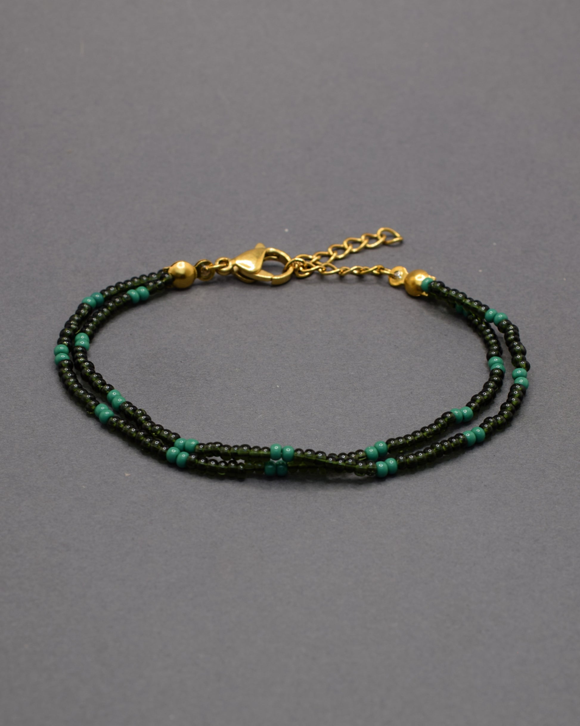 Pulseira dupla de missangas verde escuro semitransparentes em padrão elegante. Um acessório delicado e perfeito para complementar looks.