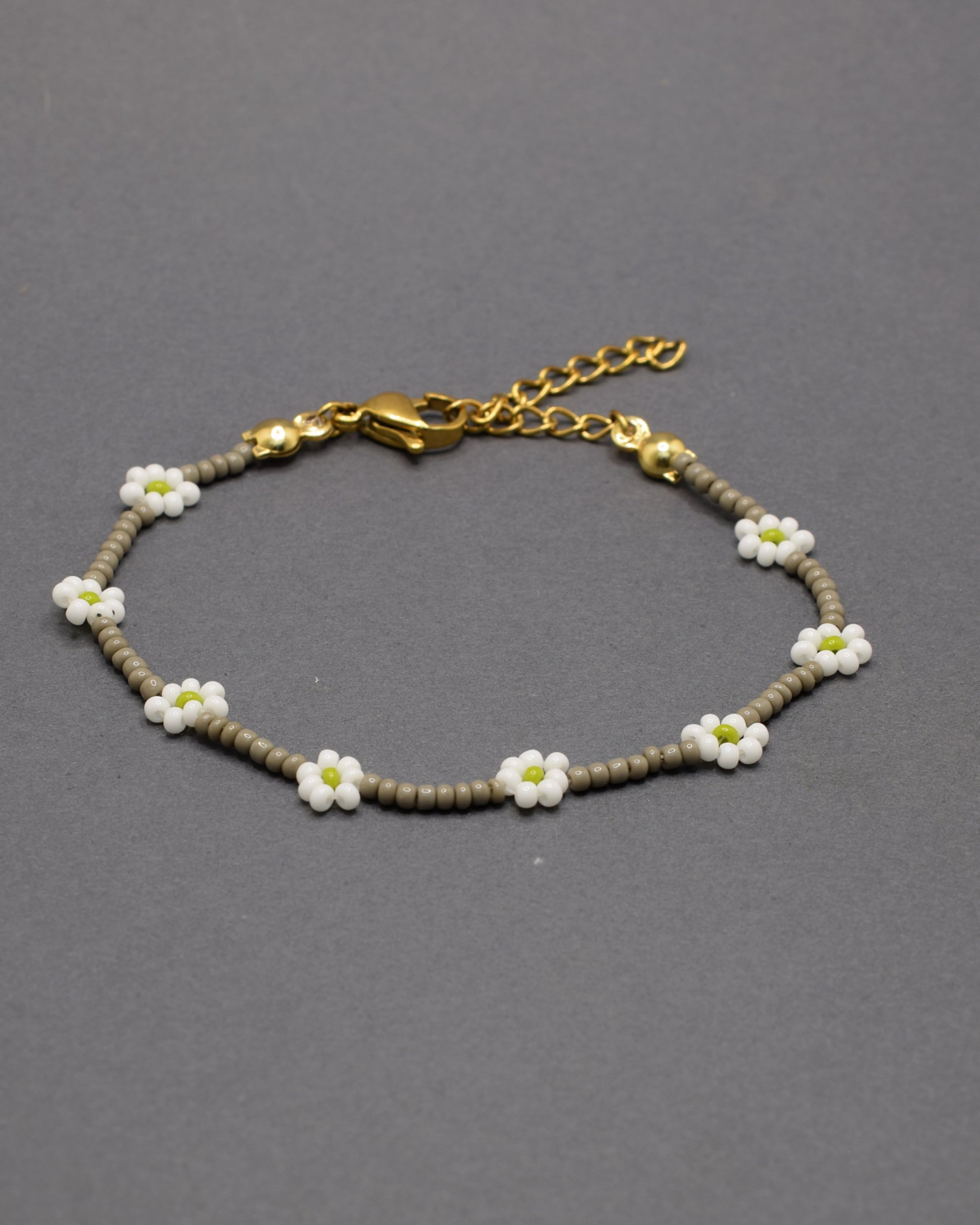 Pulseira em missangas de vidro cinzentas, com flores brancas delicadas, perfeita para um toque de elegância e charme subtil.