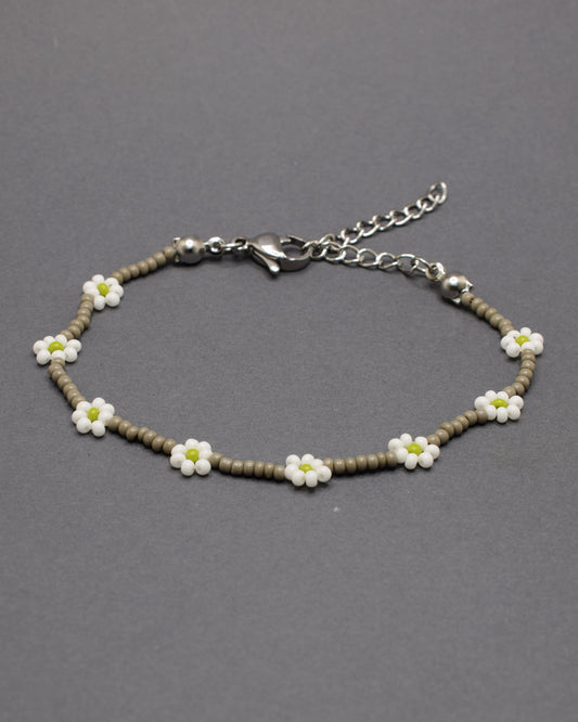 Pulseira em missangas de vidro cinzentas, com flores brancas delicadas, perfeita para um toque de elegância e charme subtil.