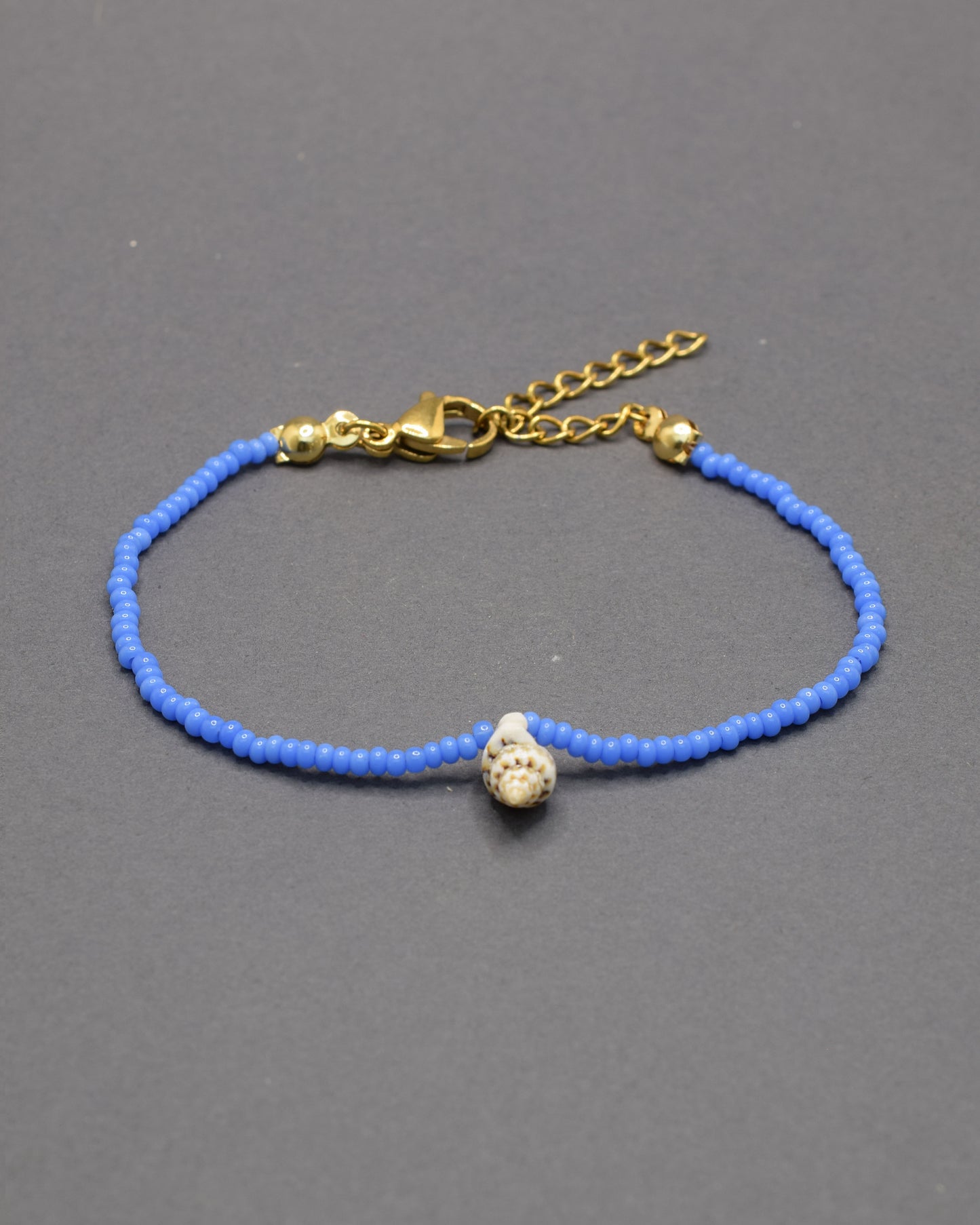 Pulseira com búzio natural e missangas de vidro azul néon, marcante e moderna, adiciona um toque distintivo e cheio de vida ao teu estilo.