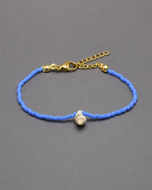 Pulseira com búzio natural e missangas de vidro azul néon, marcante e moderna, adiciona um toque distintivo e cheio de vida ao teu estilo.