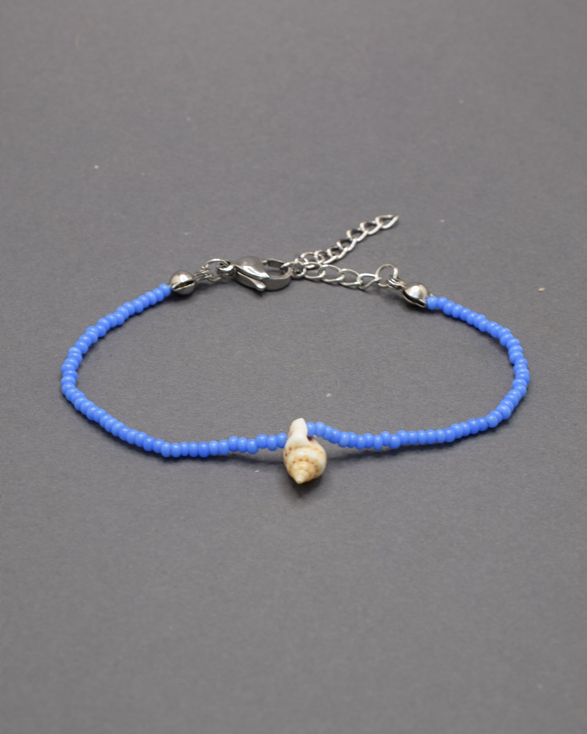Pulseira com búzio natural e missangas de vidro azul néon, marcante e moderna, adiciona um toque distintivo e cheio de vida ao teu estilo.