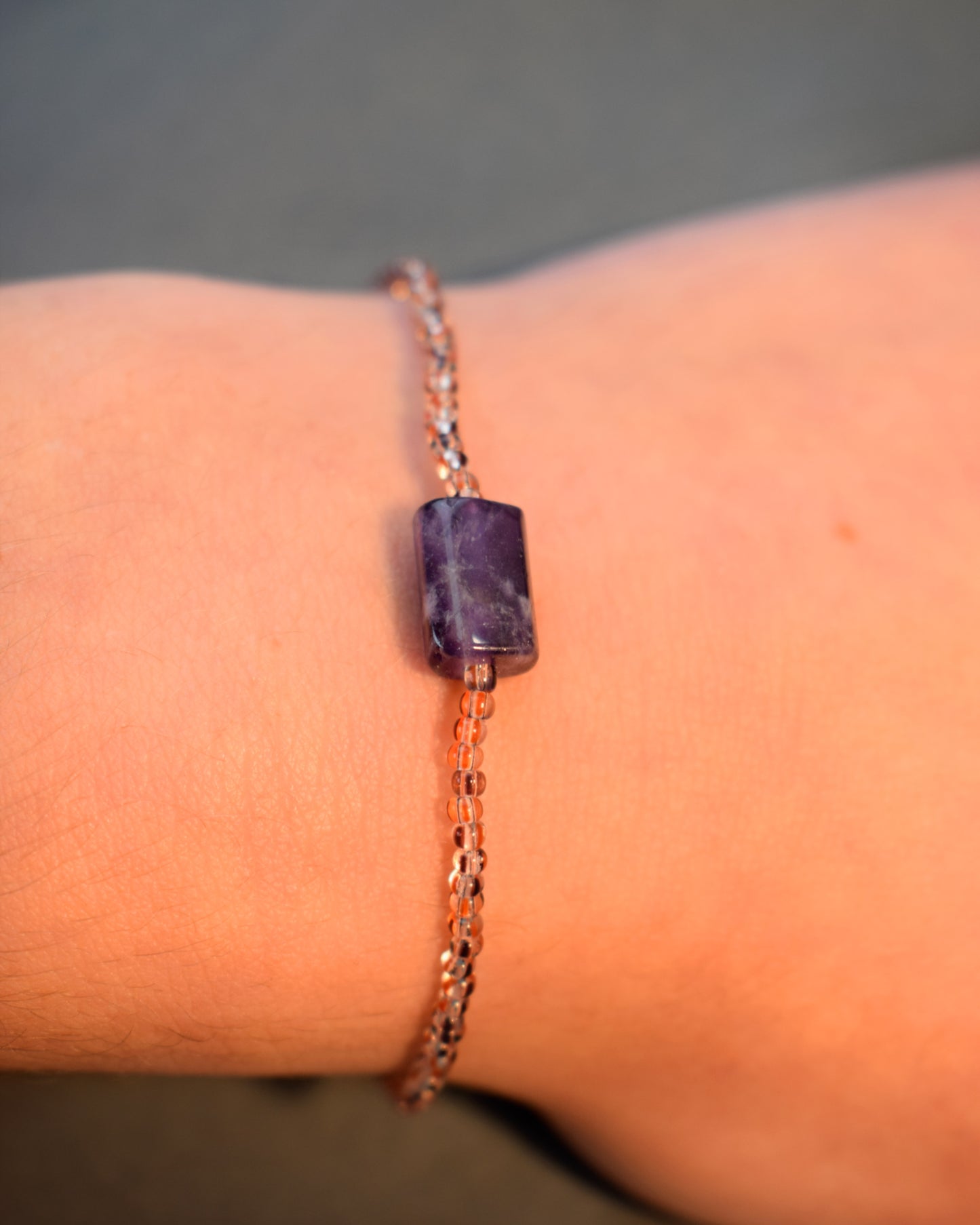 Pulseira de ametista natural, símbolo de equilíbrio e proteção, com missangas listradas castanhas.
