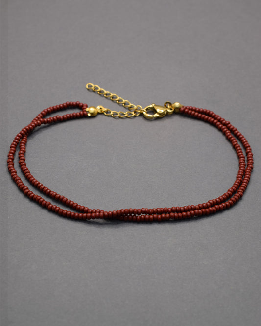 Pulseira dupla de tornozelo em missangas bordô, elegante e intensa, perfeita para um toque sofisticado e moderno no teu look.