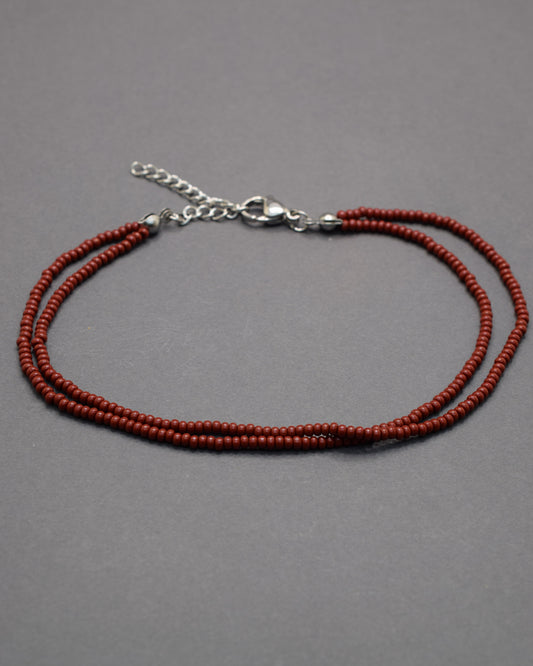 Pulseira dupla de tornozelo em missangas bordô, elegante e intensa, perfeita para um toque sofisticado e moderno no teu look.