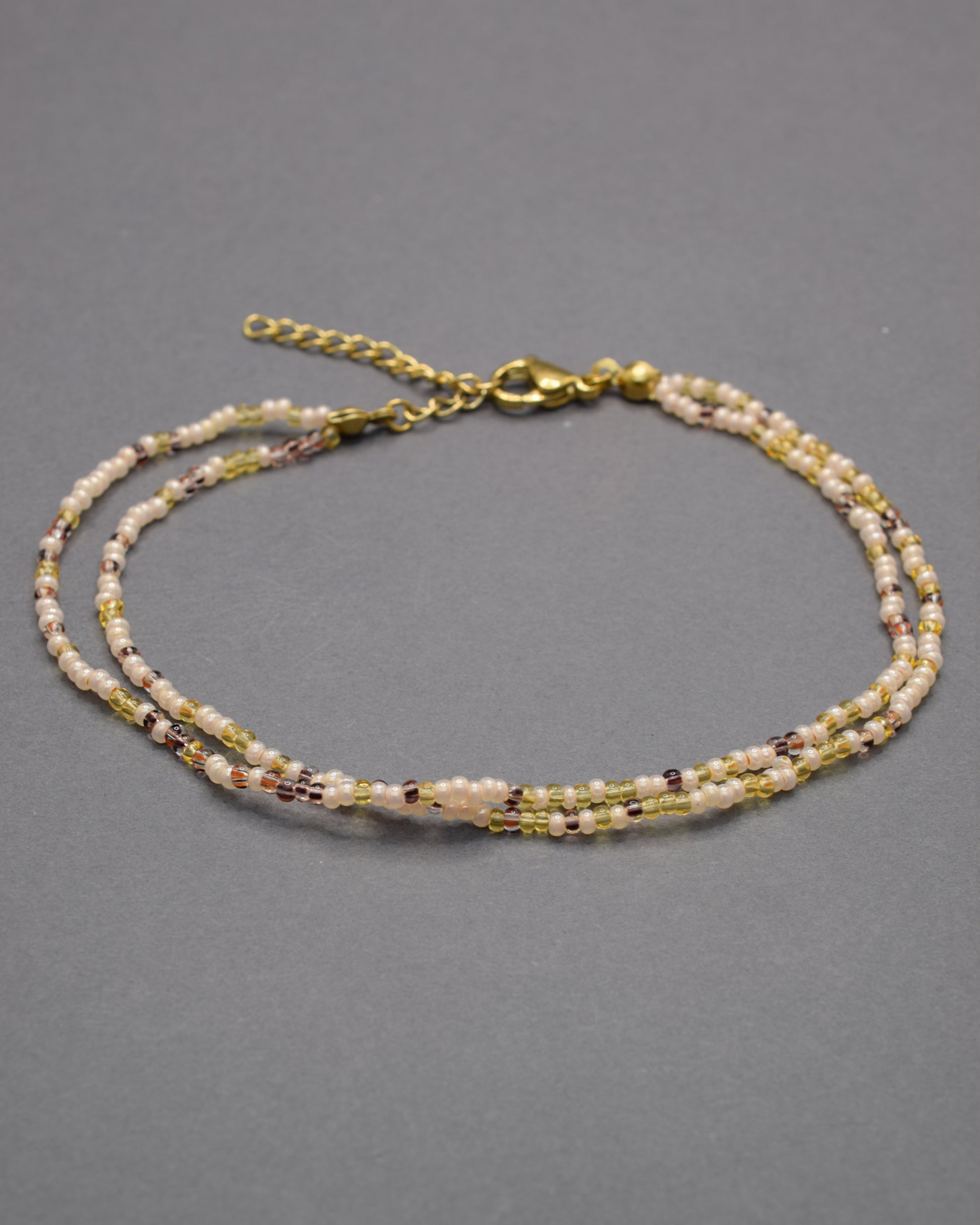 Pulseira dupla de tornozelo com missangas mix dourado, elegante e luminosa, perfeita para um toque sofisticado e cheio de charme.