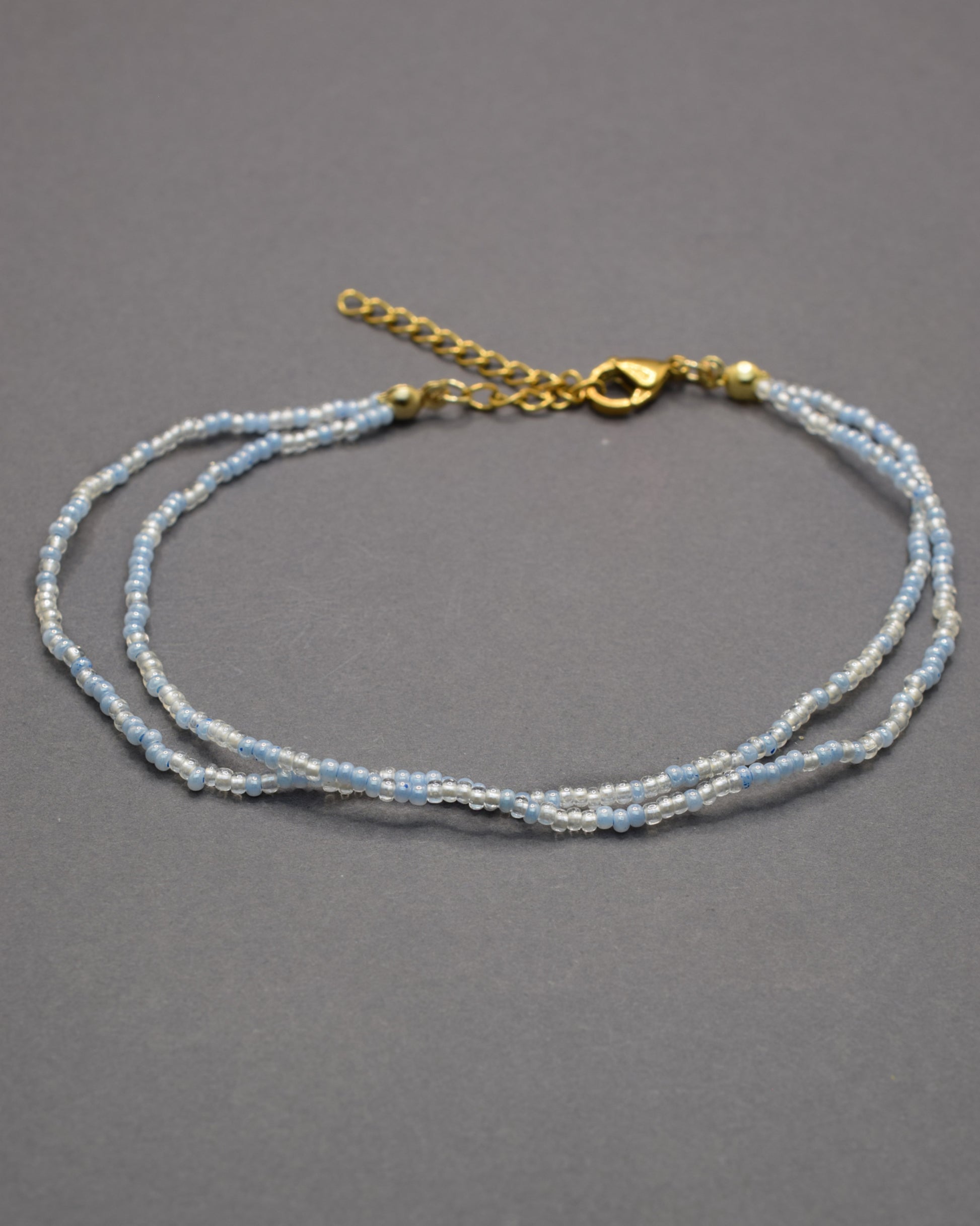 Pulseira dupla de tornozelo com missangas mix azul claro. Delicada, leve e perfeita para um look fresco e luminoso de verão.