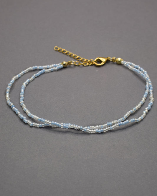 Pulseira dupla de tornozelo com missangas mix azul claro. Delicada, leve e perfeita para um look fresco e luminoso de verão.