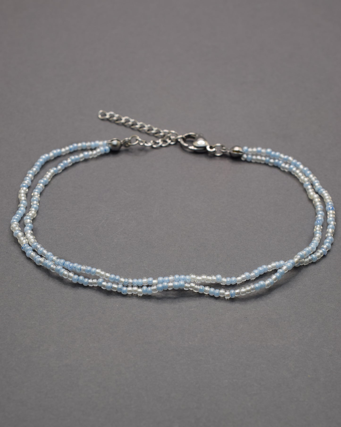 Pulseira dupla de tornozelo com missangas mix azul claro. Delicada, leve e perfeita para um look fresco e luminoso de verão.