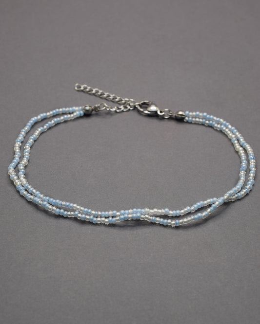 Pulseira dupla de tornozelo com missangas mix azul claro. Delicada, leve e perfeita para um look fresco e luminoso de verão.