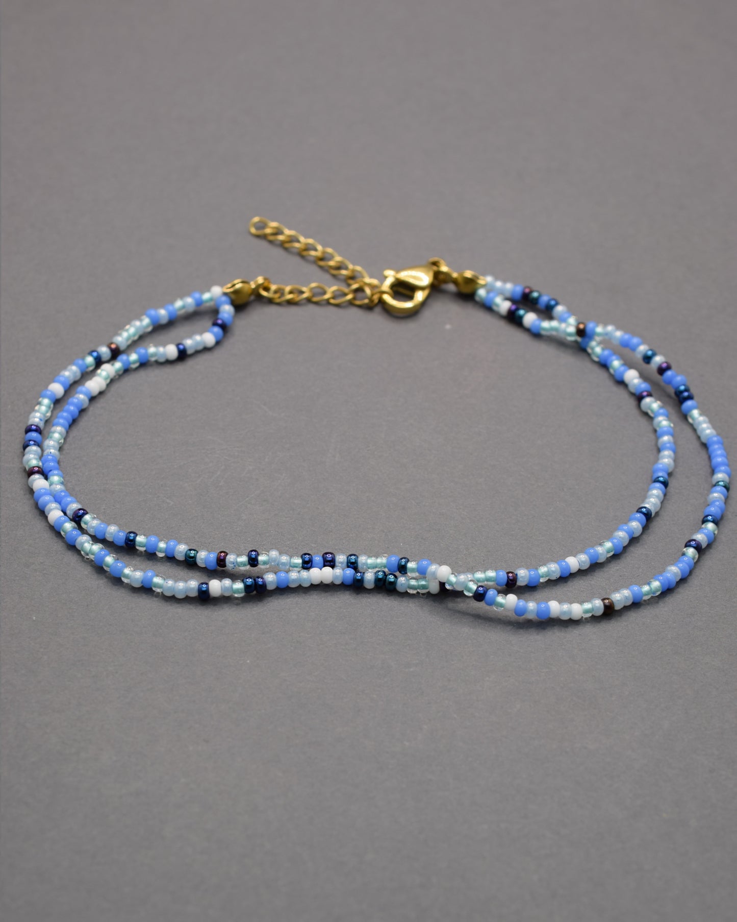 Pulseira dupla de tornozelo com missangas mix azul. Leve, vibrante e perfeita para dar um toque fresco ao teu verão.