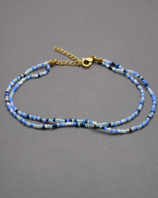 Pulseira dupla de tornozelo com missangas mix azul. Leve, vibrante e perfeita para dar um toque fresco ao teu verão.