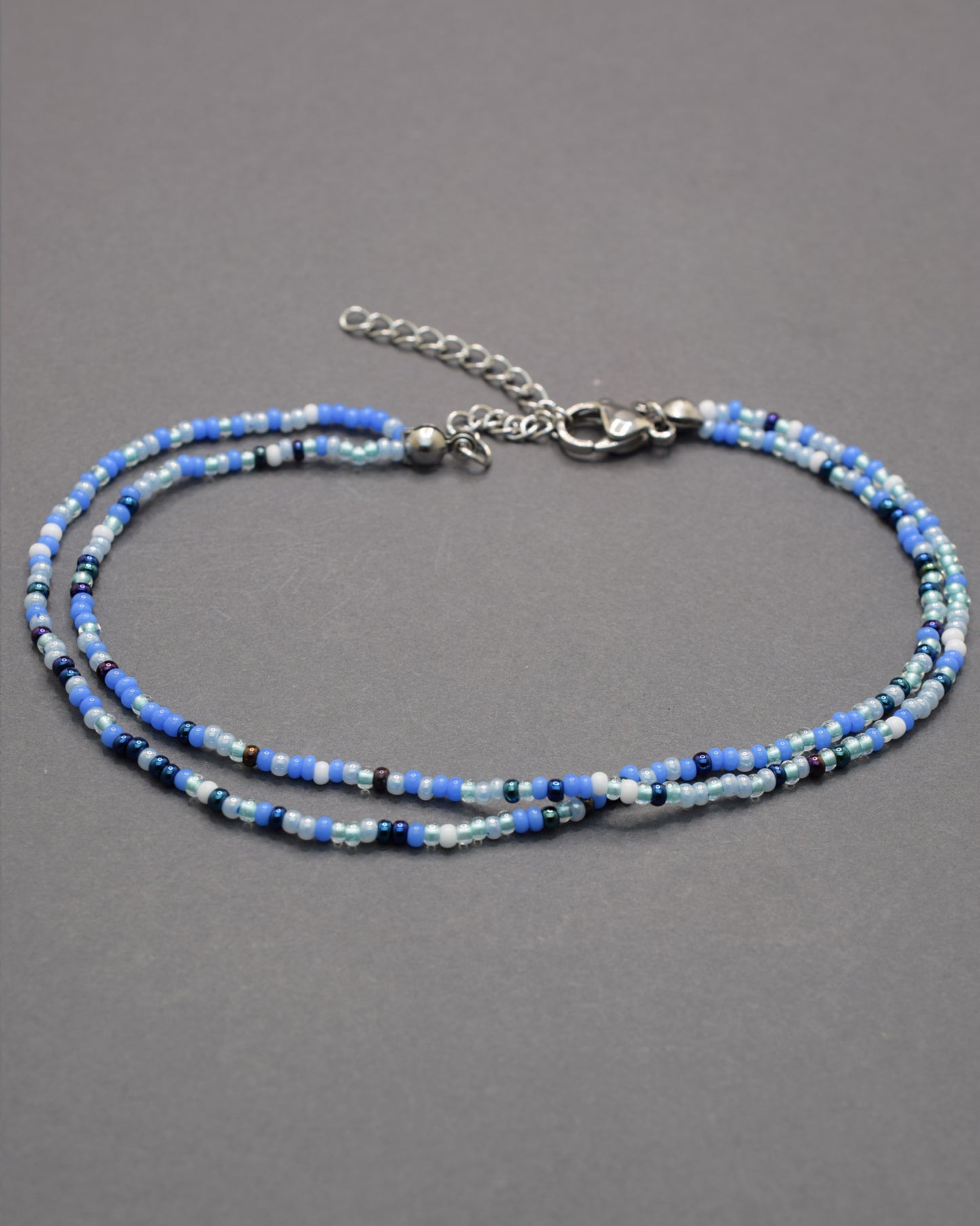 Pulseira dupla de tornozelo com missangas mix azul. Leve, vibrante e perfeita para dar um toque fresco ao teu verão.