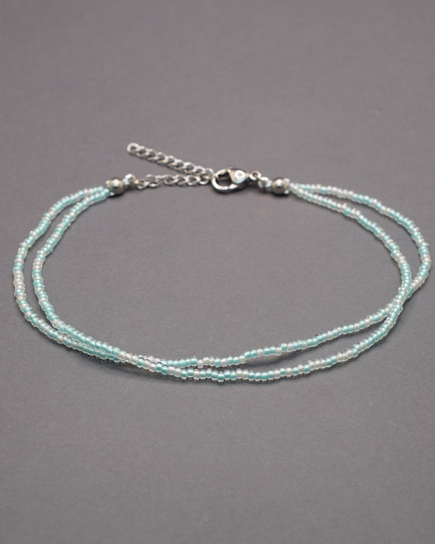 Pulseira dupla de tornozelo com missangas turquesa semitransparentes, leve e vibrante, ideal para um look fresco e cheio de estilo.