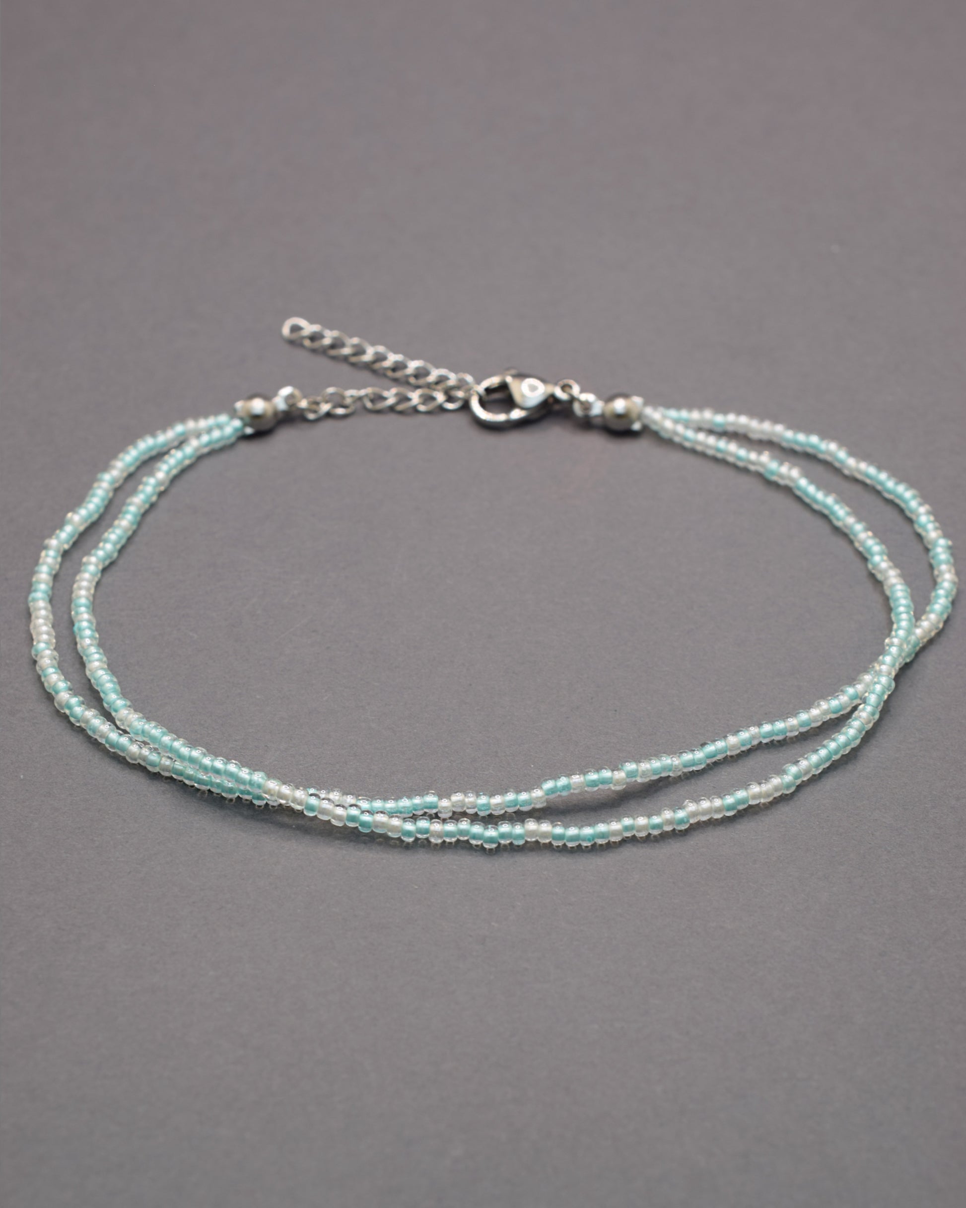 Pulseira dupla de tornozelo com missangas turquesa semitransparentes, leve e vibrante, ideal para um look fresco e cheio de estilo.