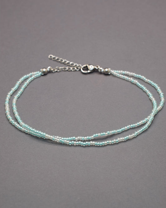 Pulseira dupla de tornozelo com missangas turquesa semitransparentes, leve e vibrante, ideal para um look fresco e cheio de estilo.