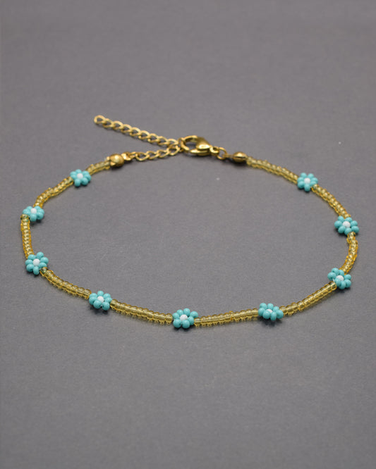 Pulseira de tornozelo com flores turquesa e missangas douradas semitransparentes, leve e vibrante, perfeita para um estilo fresco e luminoso.