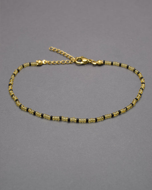 Pulseira de tornozelo com missangas douradas semitransparentes e padrão preto, elegante e moderna, perfeita para destacar o teu estilo.