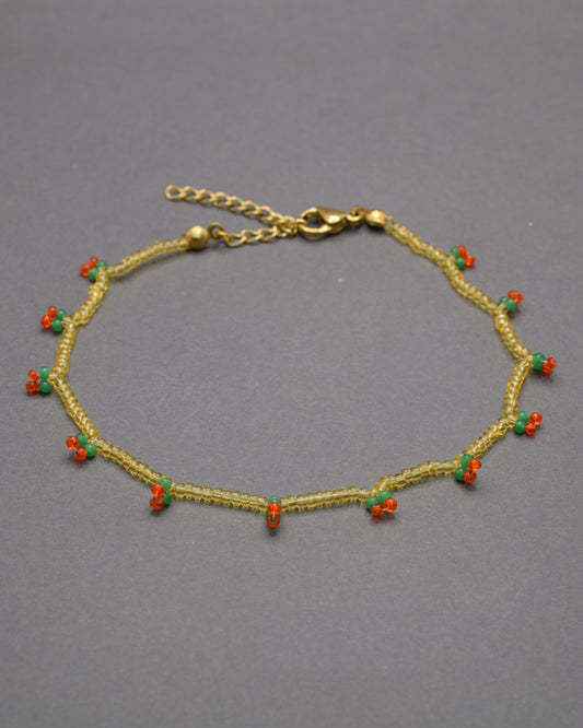 Pulseira de tornozelo com cerejas em missangas douradas semitransparentes, delicada e divertida, perfeita para um toque doce e brilhante.
