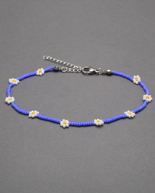 Pulseira de tornozelo em missangas azul néon com flores brancas. Leve, vibrante e perfeita para dar um toque divertido e moderno ao teu look.