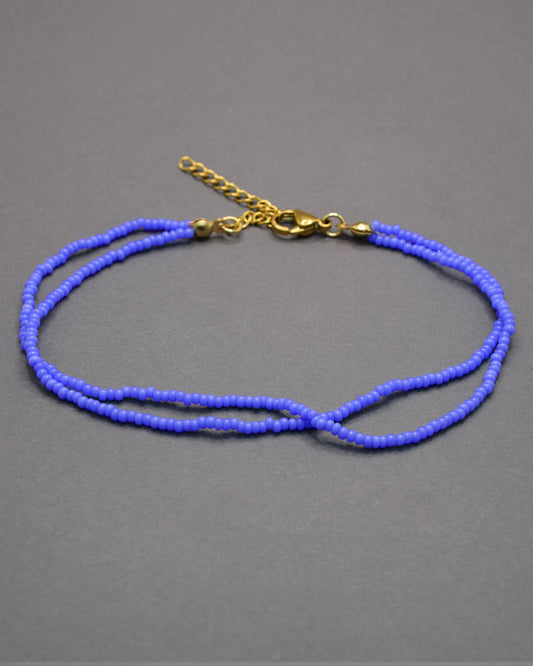 Pulseira dupla de tornozelo em missangas de vidro azul neon, leve e vibrante, perfeita para destacar o teu estilo com um toque moderno e luminoso.