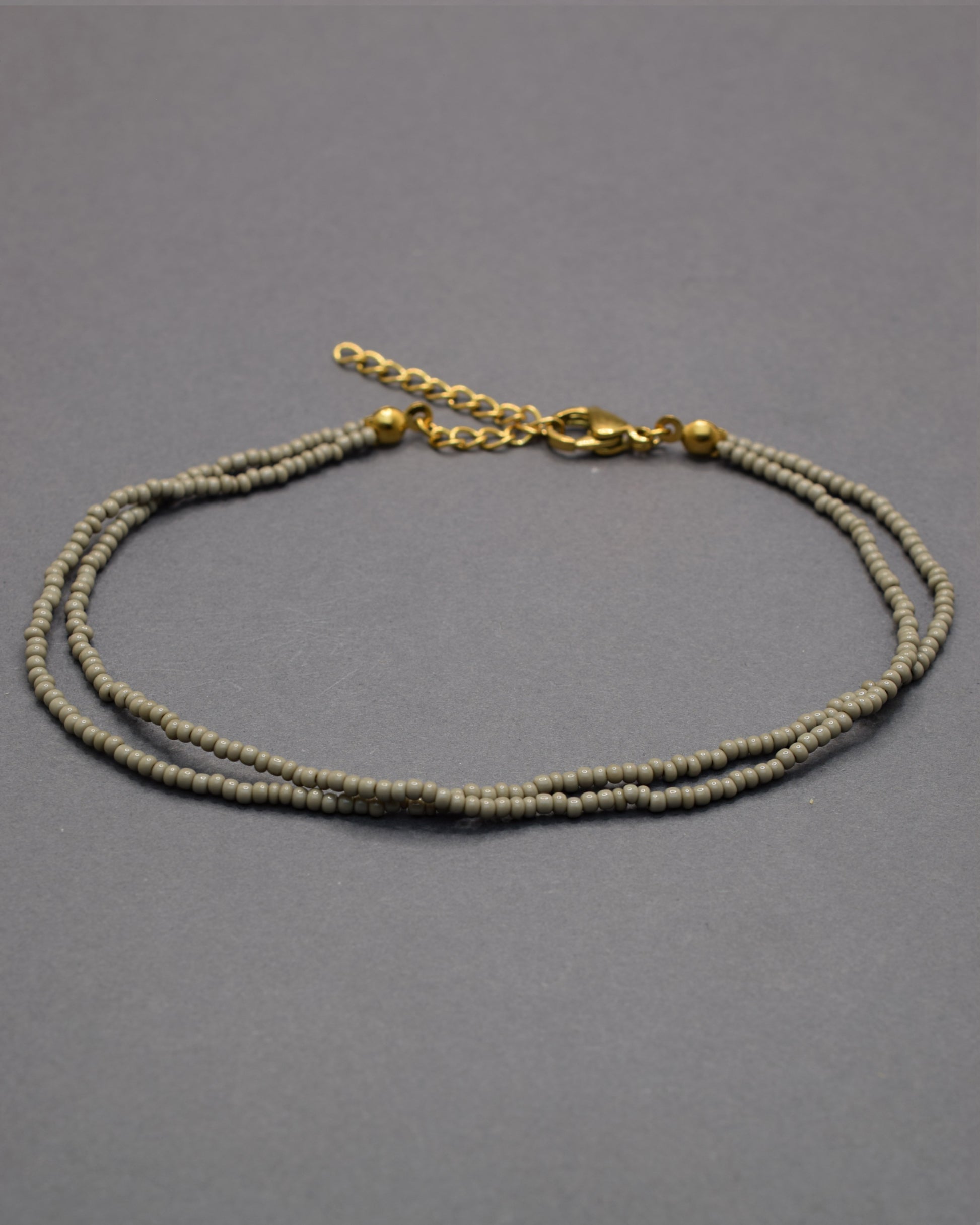 Pulseira dupla de tornozelo com missangas cinzentas. Elegante, discreta e perfeita para complementar qualquer look com estilo moderno.