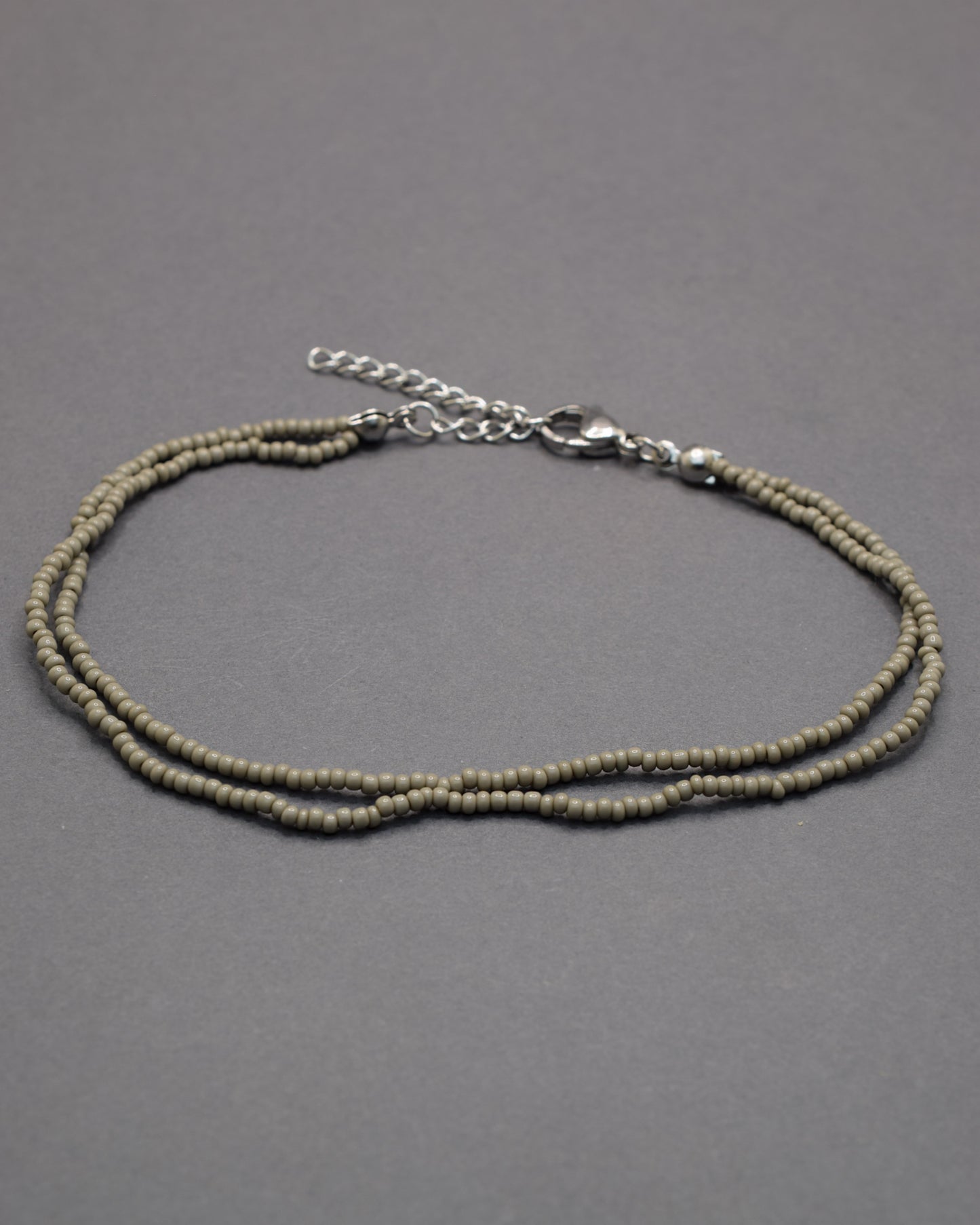 Pulseira dupla de tornozelo com missangas cinzentas. Elegante, discreta e perfeita para complementar qualquer look com estilo moderno.