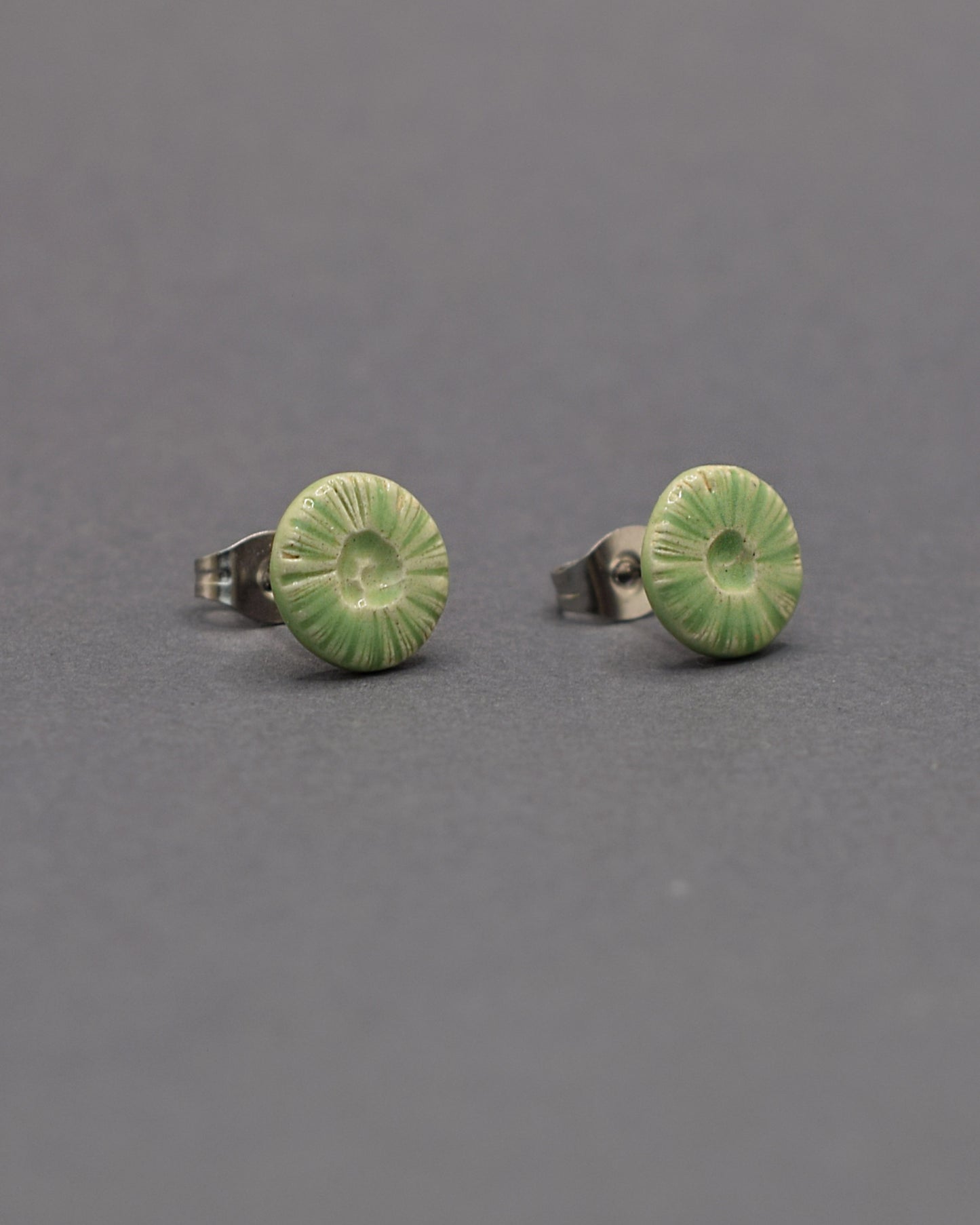 Brincos stud em cerâmica, com design flor do mar em verde claro. Perfeitos para um toque único e moderno no seu look.