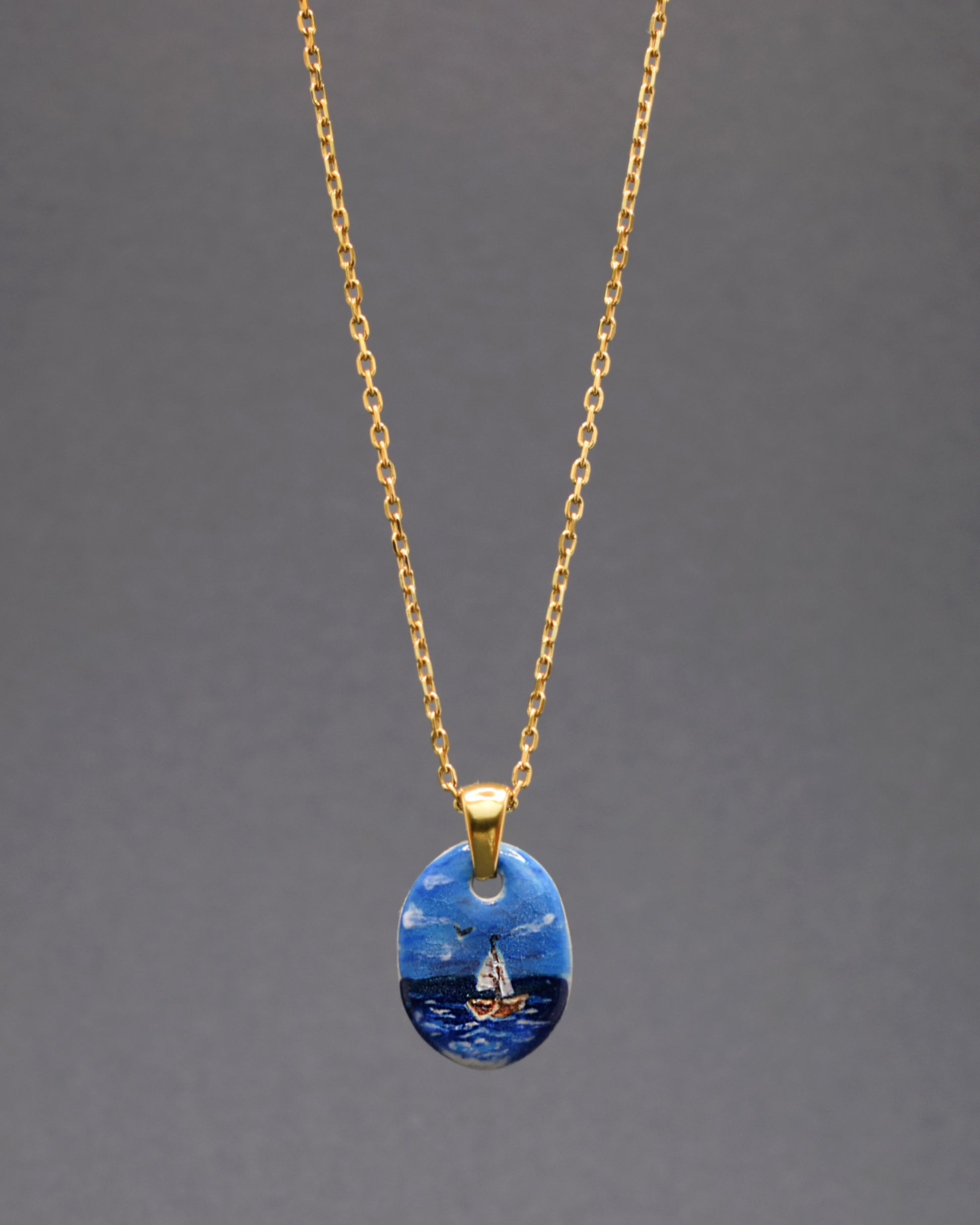 Radiante em cada detalhe! Apresentamos o nosso colar exclusivo com um pendente de cerâmica - um magnífico Barco em Alto Mar, perfeitamente complementado pela corrente de aço inoxidável dourado. Um toque de sofisticação que ilumina o seu estilo.